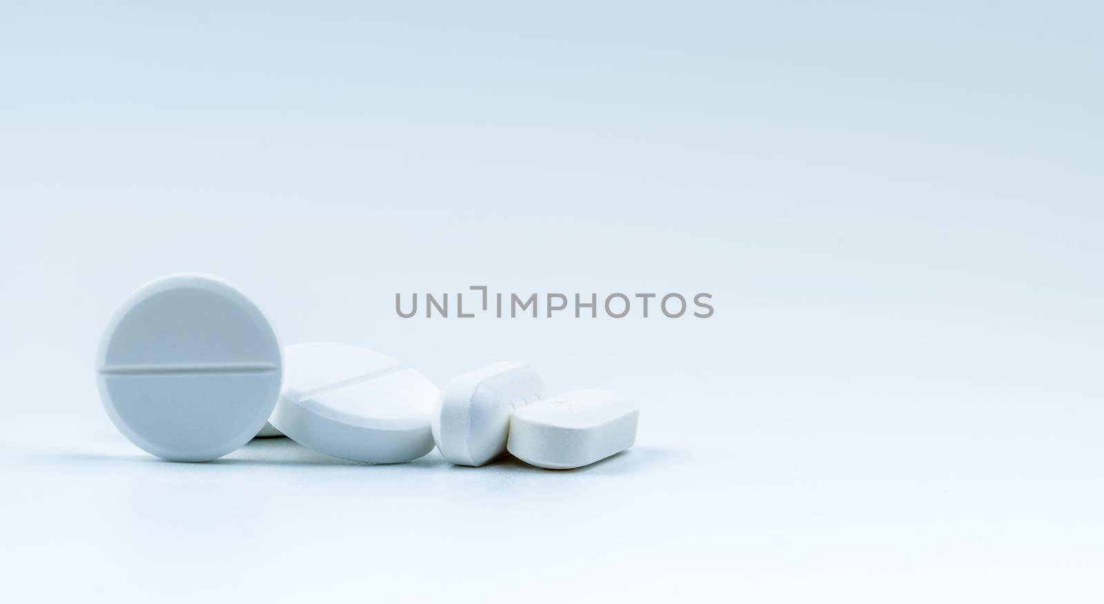 Pile of white round and oblong shape tablet pills isolated on white background. Pharmaceutical industry. Pharmacy or drugstore sign and symbol. Global healthcare concept. Health and pharmacology. by Fahroni