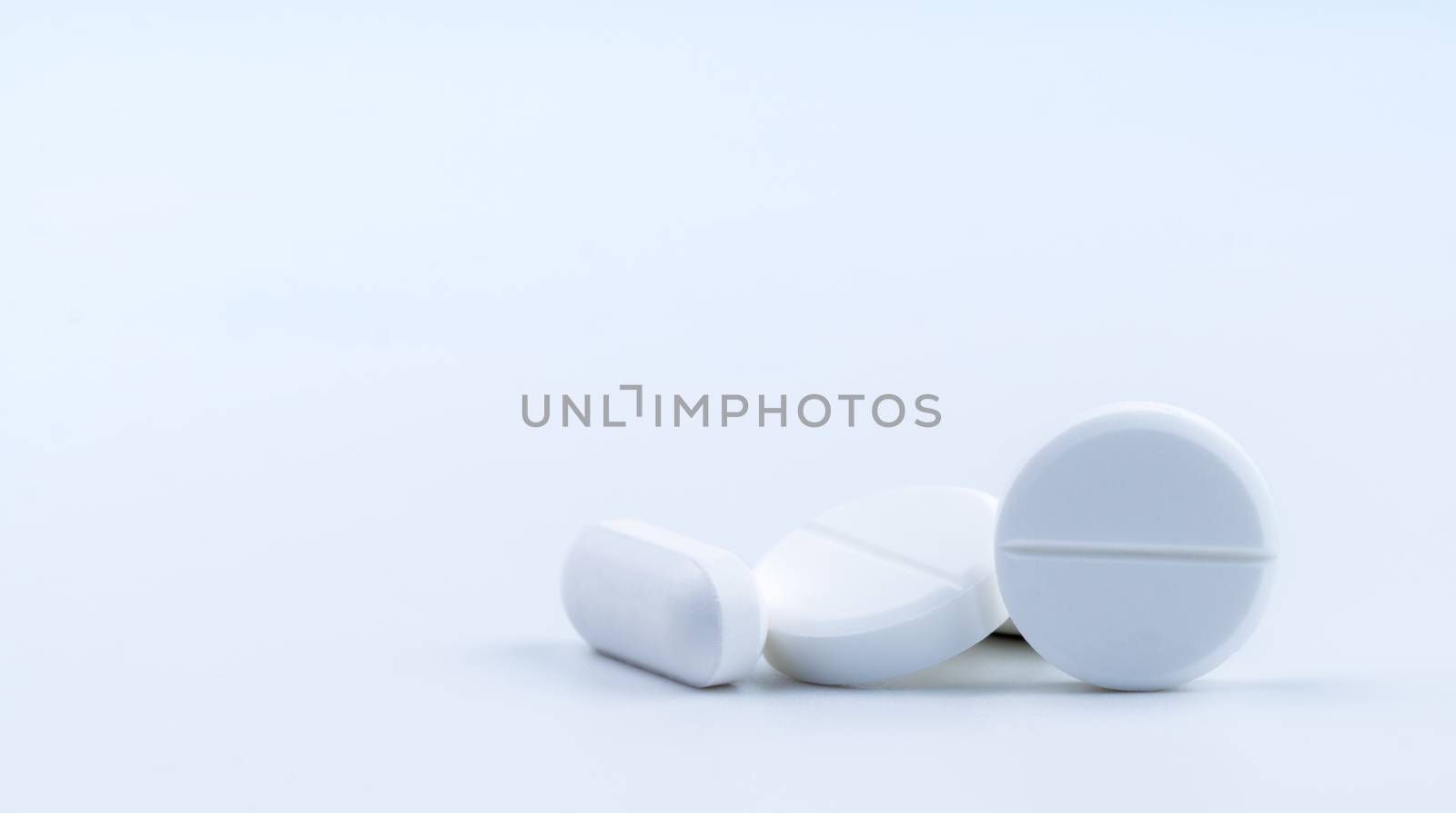 Pile of white round and oblong shape tablet pills isolated on white background. Pharmaceutical industry. Pharmacy or drugstore sign and symbol. Global healthcare concept. Health and pharmacology.