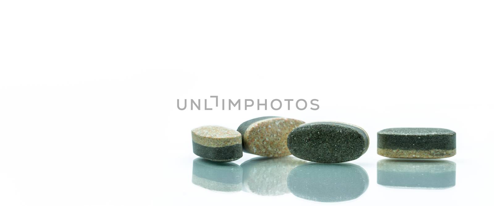 Essential Vitamins and minerals supplements dual layer tablet pills isolated on white background. Multivitamins plus reishi mushroom, wheatgrass, white tea and organic spirulina. Whole food nutrients.