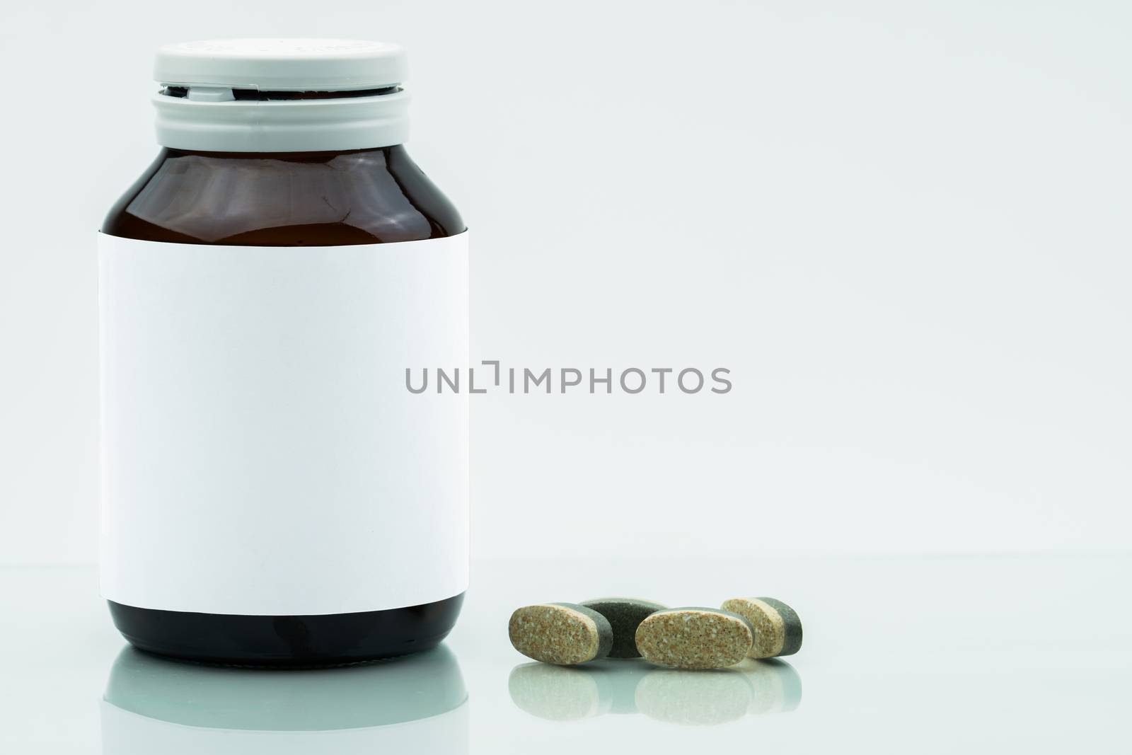 Vitamins, supplements and minerals dual layer tablets pills and medicine amber glass bottle with blank label isolated on white background with copy space. Use for vitamins and supplements advertising.