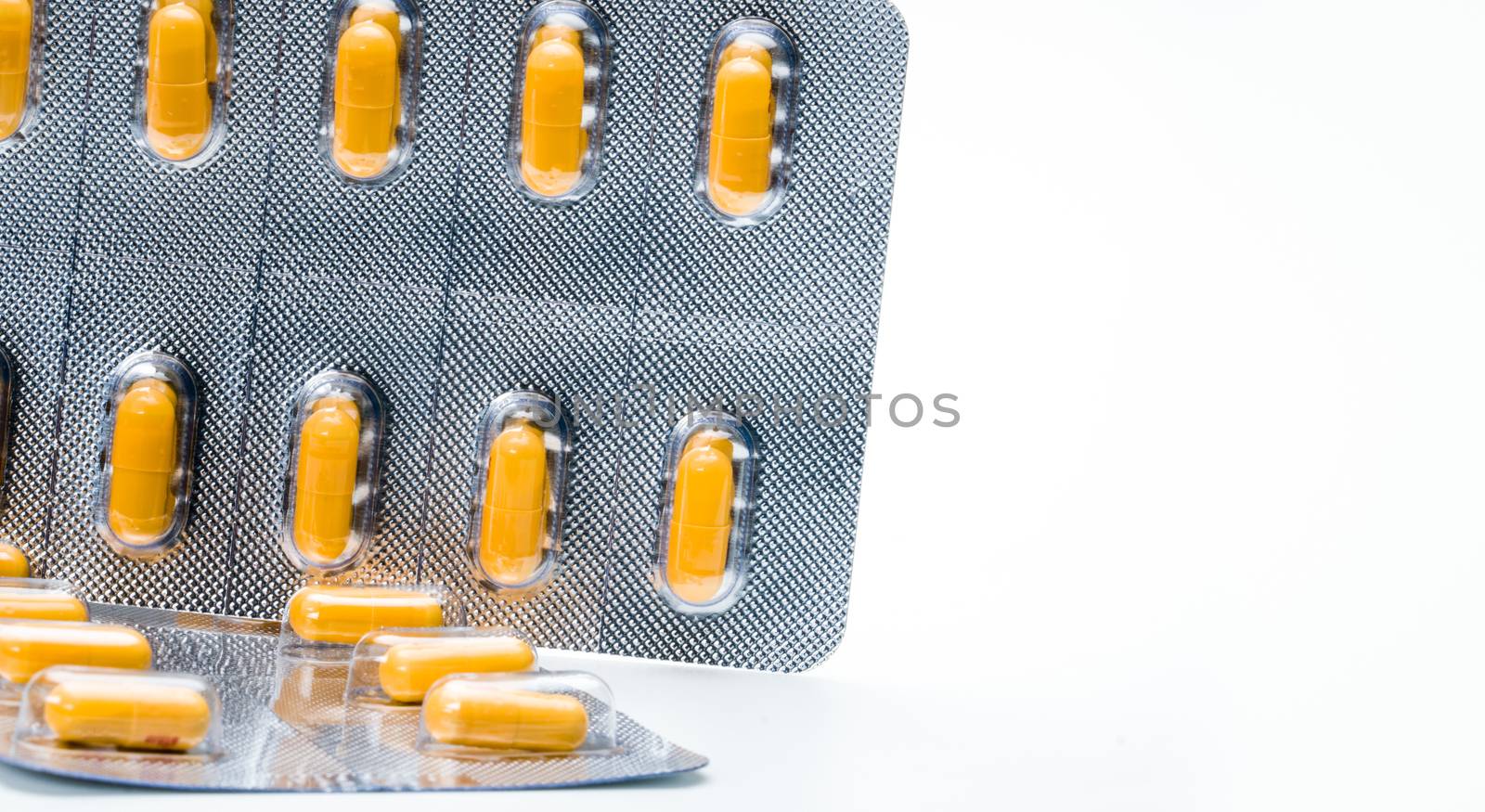 Orange capsule pills in blister pack isolated on white background with copy space for text. Antibiotics drug resistance and antimicrobial drug use with reasonable concept. Global healthcare. Pharmaceutical packaging industry. Pharmacy background. by Fahroni