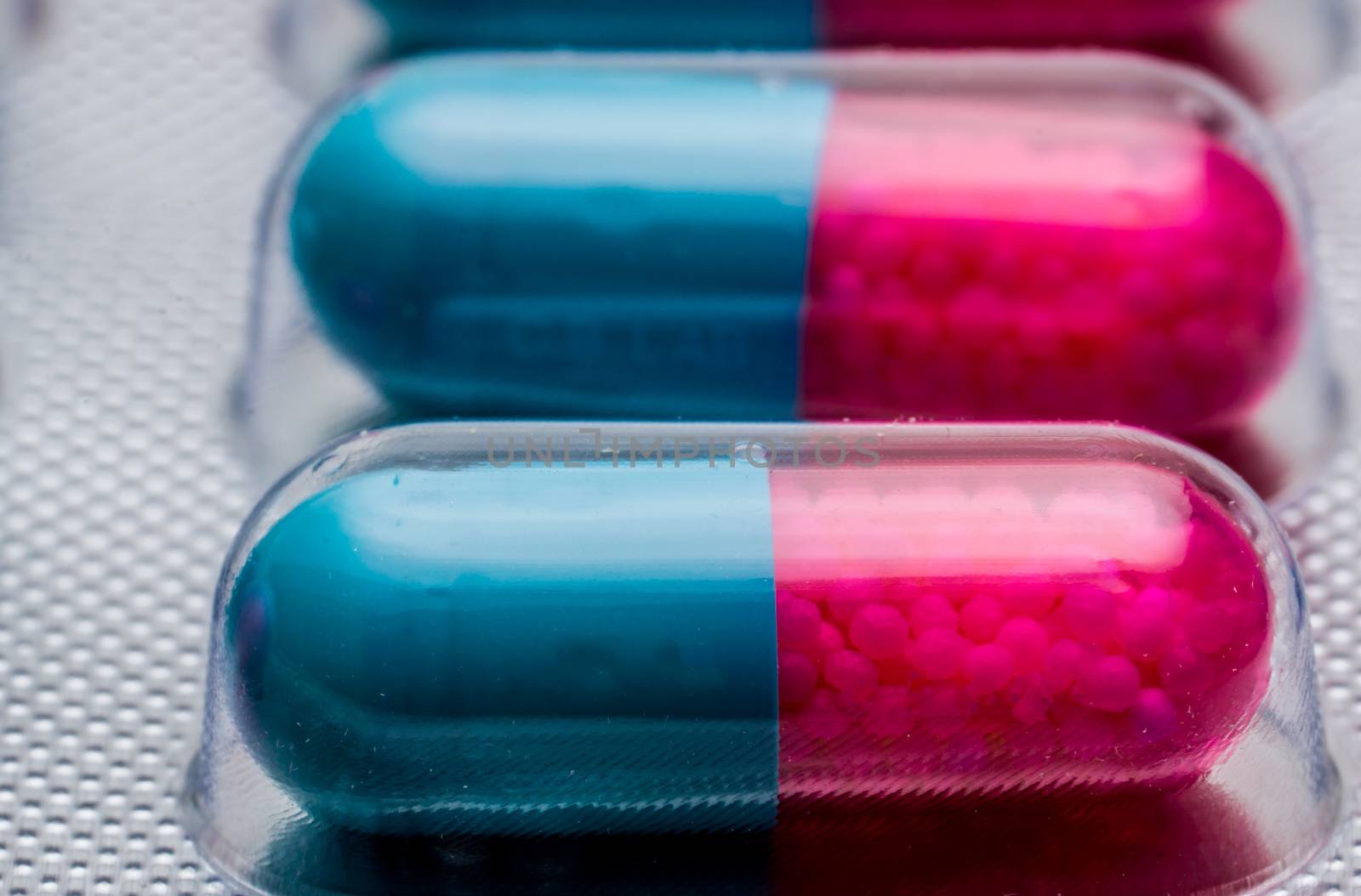 Macro shot detail of blue, pink capsule with granule in side pills. Pills in blister pack. Pharmaceutical dosage form and packaging. Itraconazole 100 mg : Anti-fungal medicine. Pharmaceutical industry. Pharmacy background.