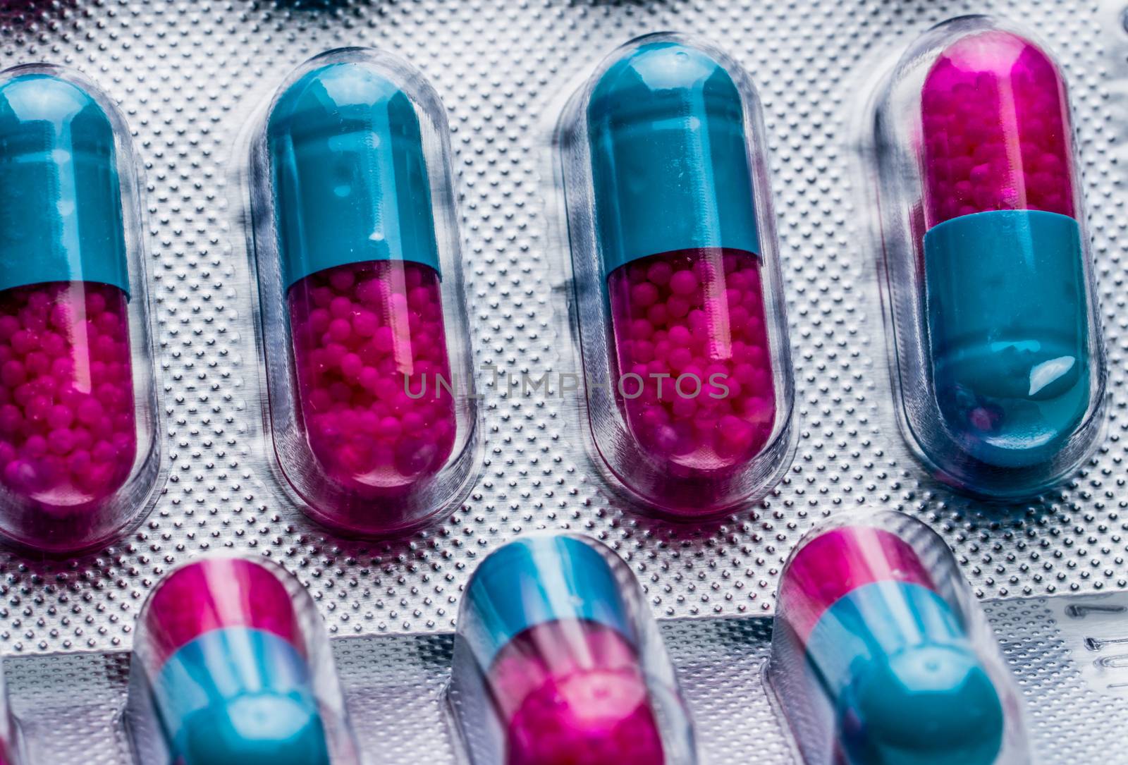 Macro shot detail of blue, pink capsule with granule in side pills. Pills in blister pack. Pharmaceutical dosage form and packaging. Itraconazole 100 mg : Anti-fungal medicine. Pharmaceutical industry. Pharmacy background. Global healthcare concept. by Fahroni