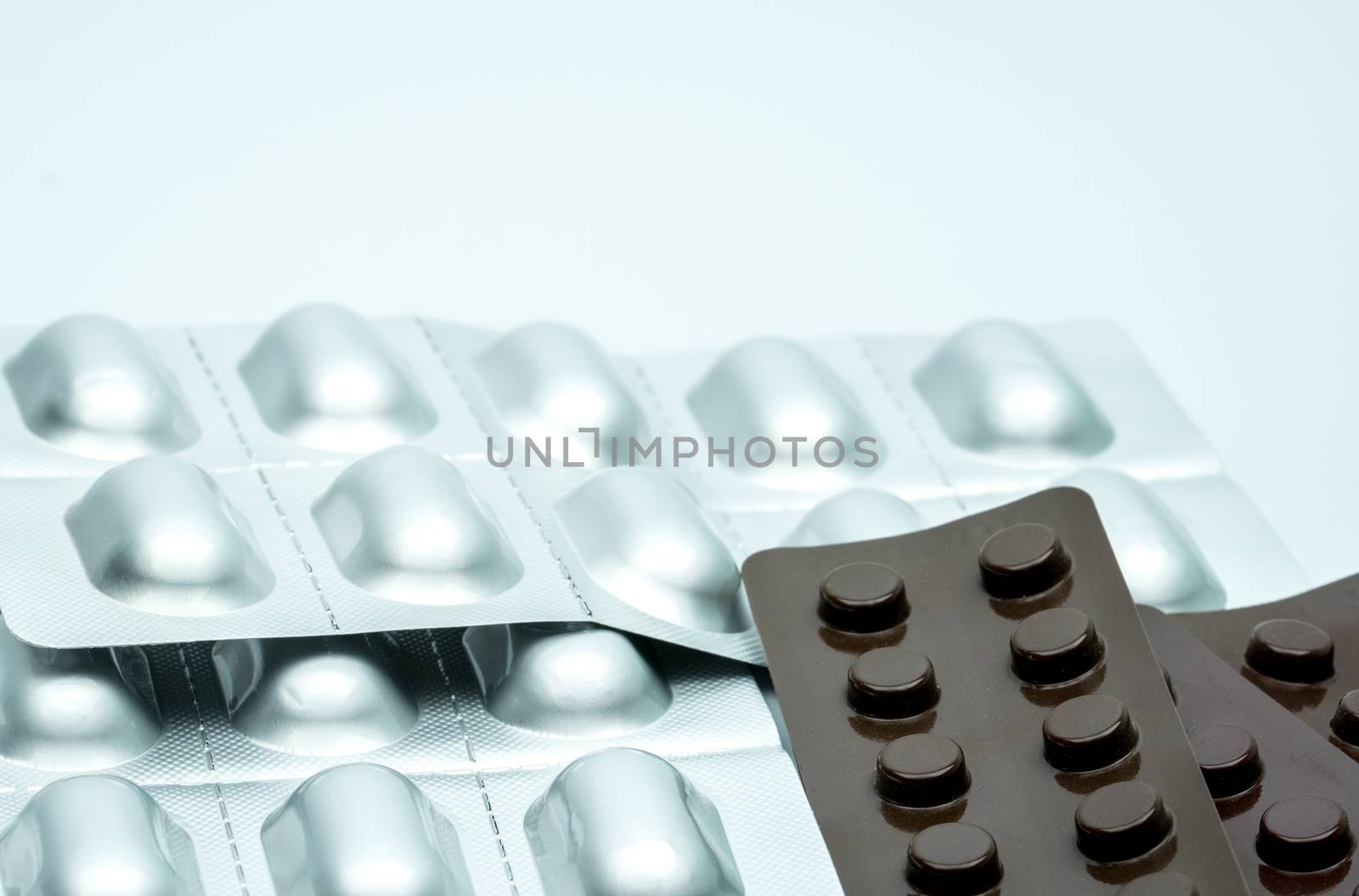 Silver aluminium blister pack and brown blister pack for light resistance packaging to protect drug degradation. Tablet pills packaging isolated on white background. Pharmaceutical industry. Pharmacy background. Global healthcare. Health budgets and policy concept.