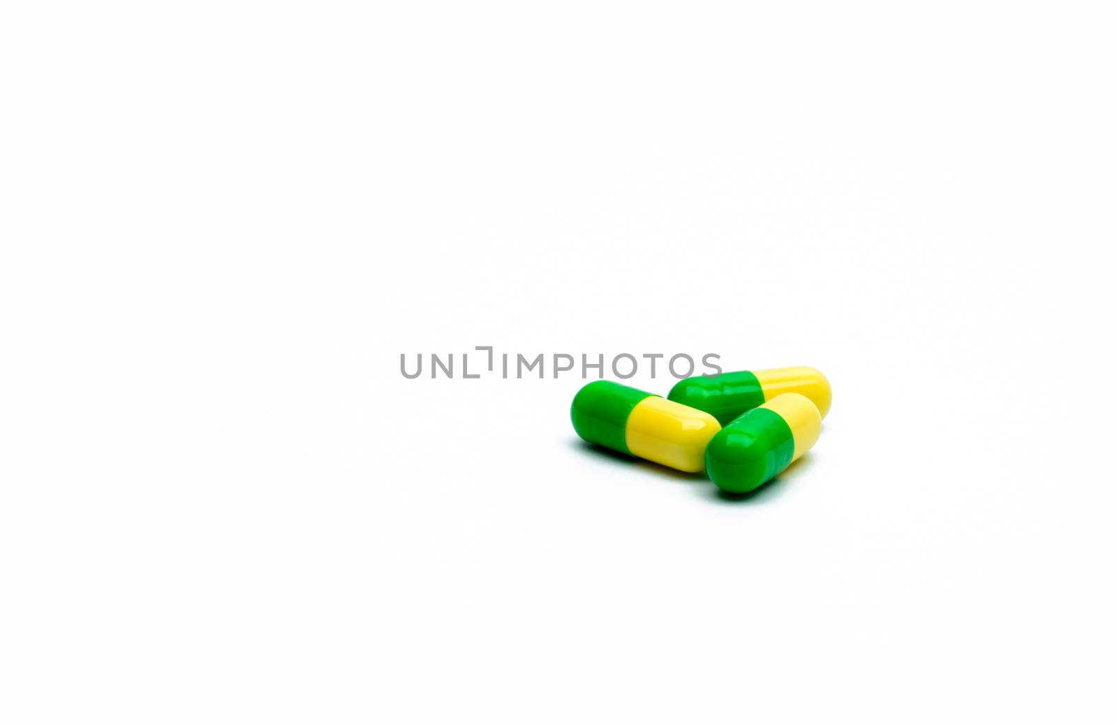 Green, yellow tramadol capsule pills on white background with shadows and copy space. Cancer pain management. Opioid analgesics. Drug abuse in teenage in Thailand. Pharmaceutical industry. Pharmacy background. Global healthcare concept. by Fahroni