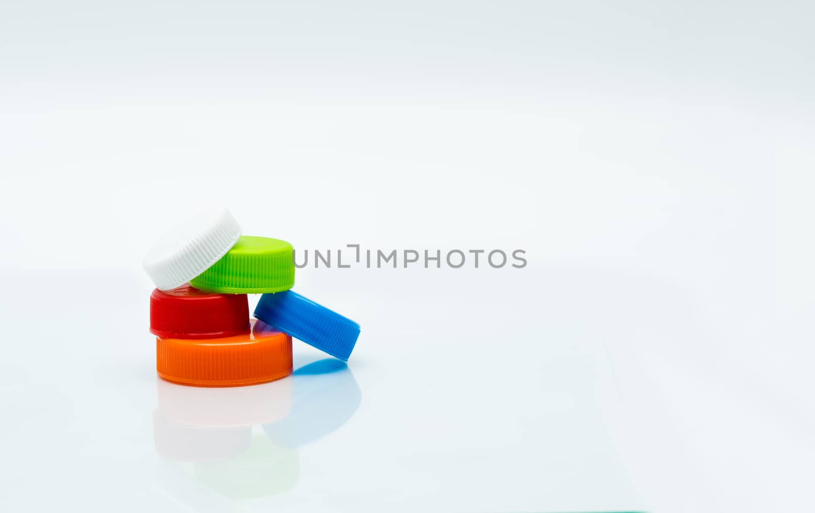 Pile of different size of white, green, red, blue and orange color round plastic screw caps on white background and copy space. by Fahroni