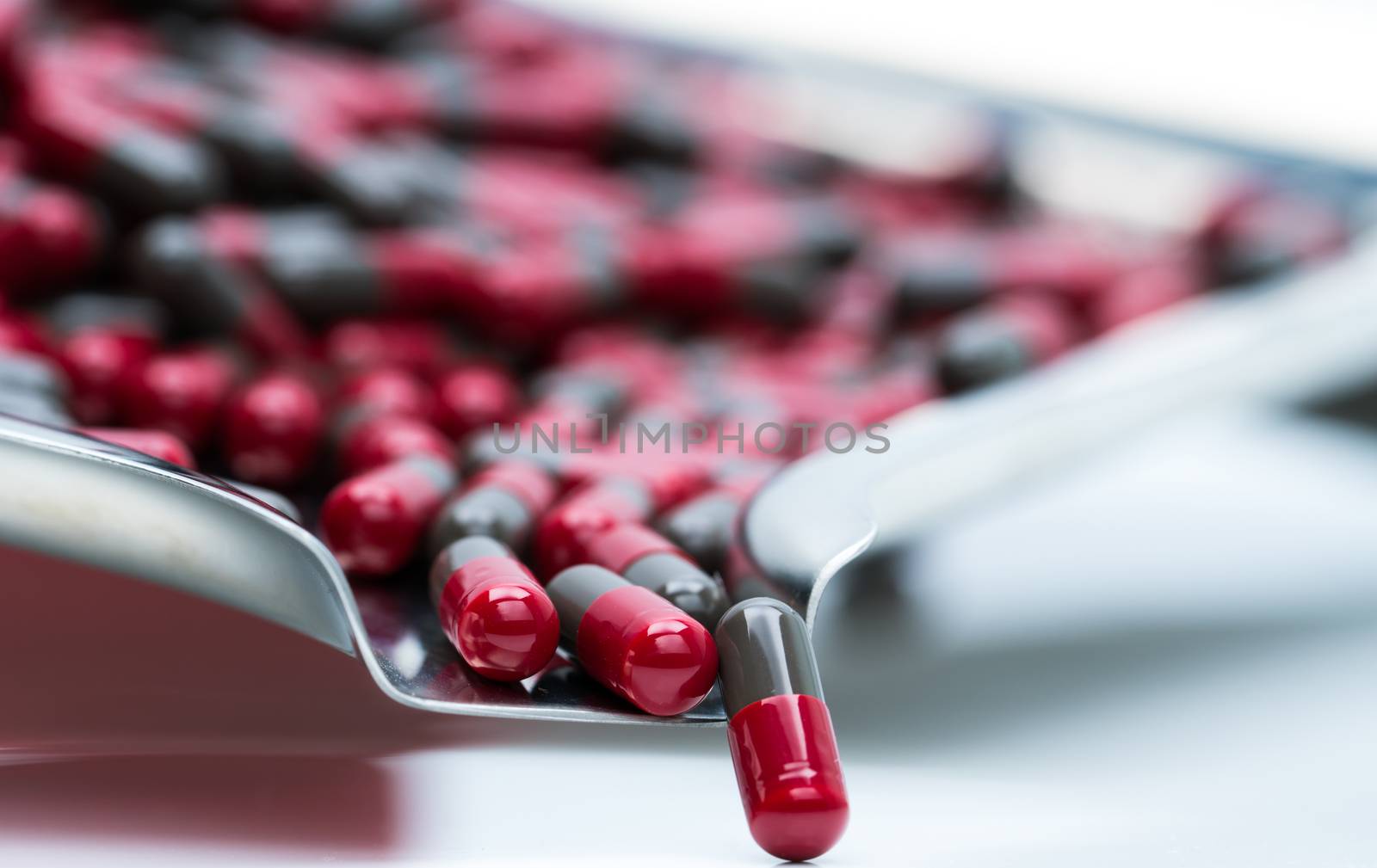 Macro shot detail selective focus of red and grey capsule pills isolated on stainless steel drug tray. Migraine prophylaxis treatment concept. Global healthcare concept. Pharmaceutical industry. Pharmacy background.