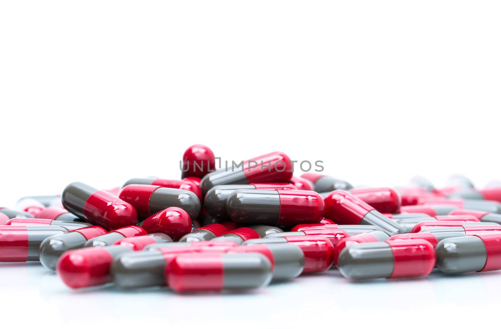 Macro shot detail selective focus of red and grey capsule pills isolated on white background with copy space for text. Migraine prophylaxis treatment concept. Pharmaceutical industry. Pharmacy background. Global healthcare concept.