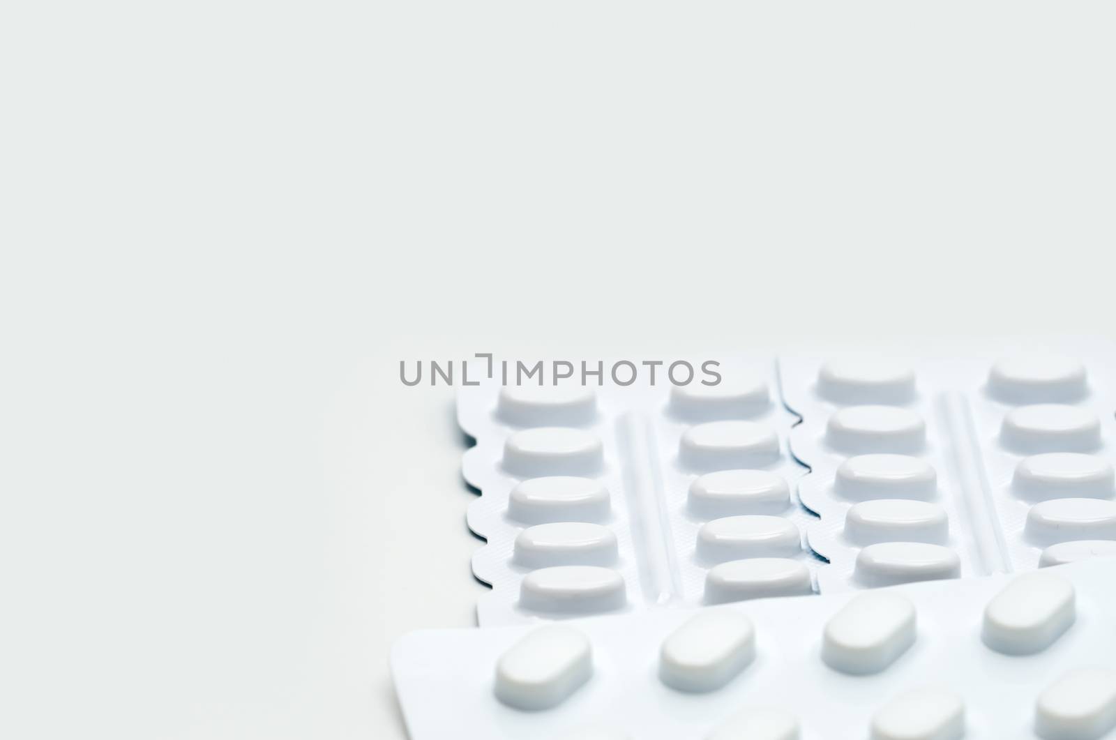 Macro shot detail of tablets pill in white blister pack for light resistance packaging isolated on white background. Medicine for treatment NCDs. Elderly people disease. Pharmaceutical industry. Pharmacy background. Global healthcare concept.