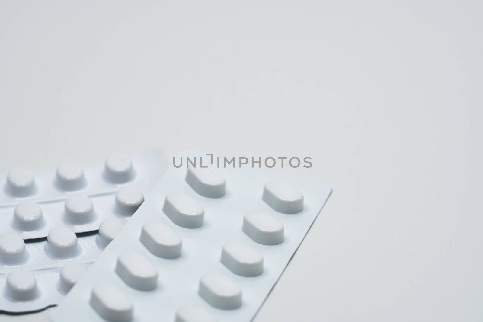 Macro shot detail of tablets pill in white blister pack for light resistance packaging isolated on white background. Medicine for treatment NCDs. Elderly people disease. Pharmaceutical industry. Pharmacy background. Global healthcare concept. Health budgets and policy.