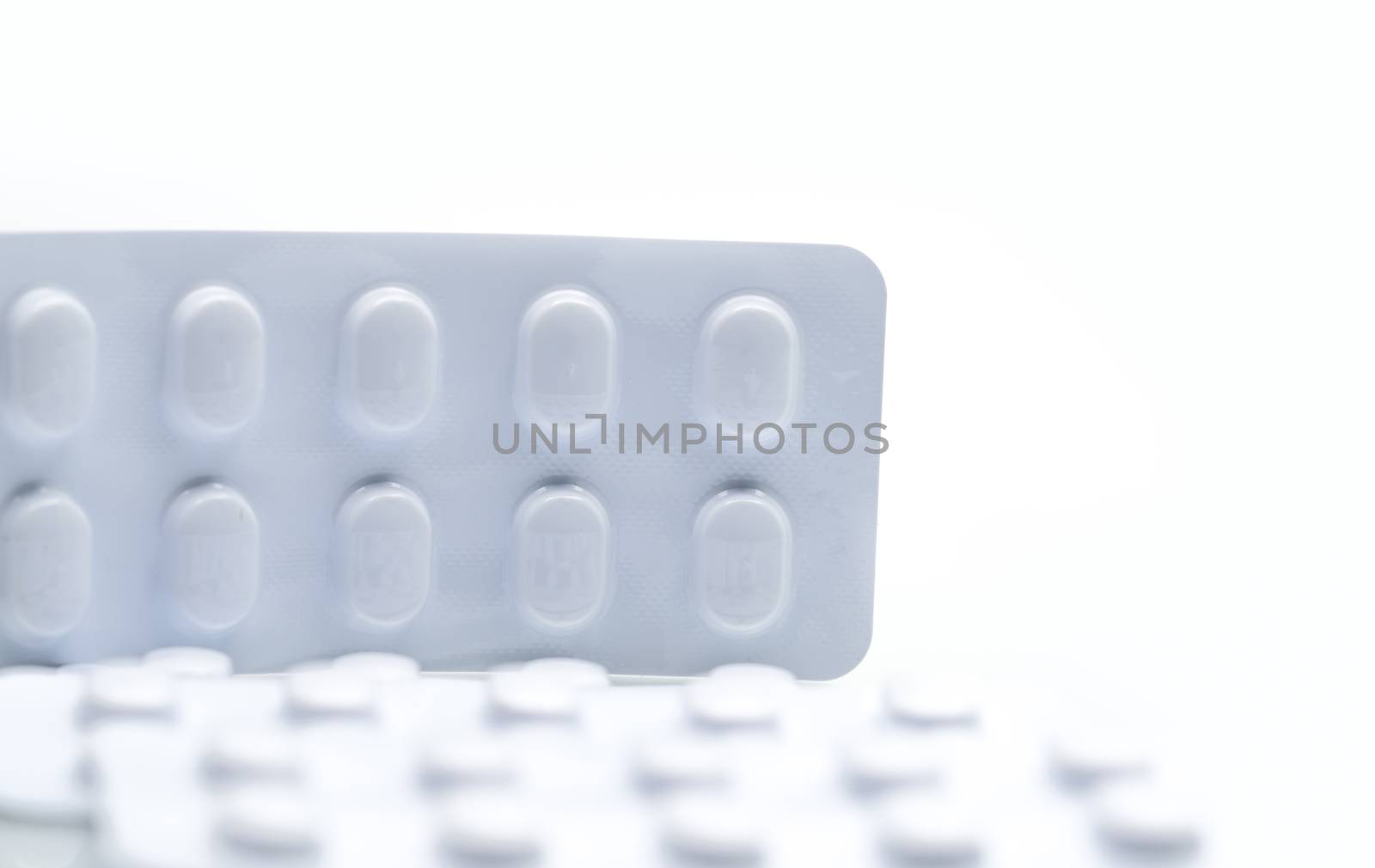 Macro shot detail of tablets pill in white blister pack for light resistance packaging isolated on white background. Medicine for treatment NCDs. Elderly people disease. Pharmaceutical industry. Pharmacy background. Global healthcare concept. Health budgets and policy. by Fahroni
