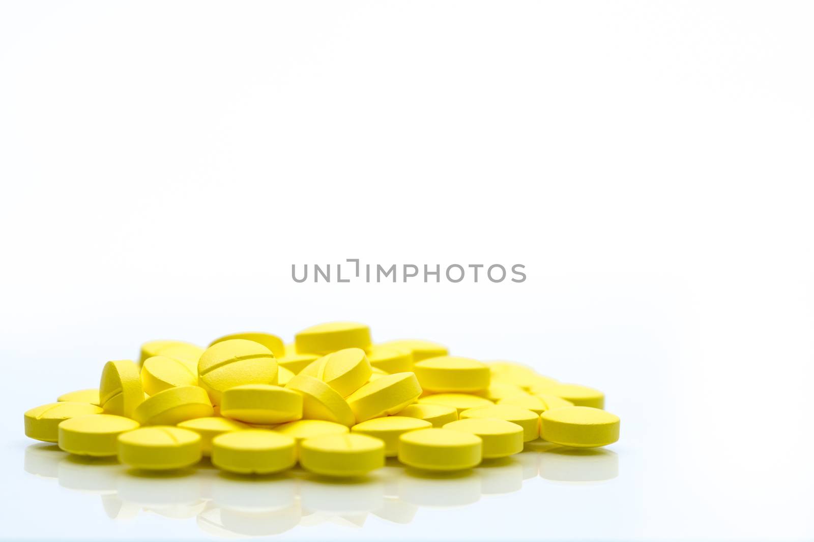 Yellow tablets pills isolated on white background with copy space. Pile of medicine. Painkiller tablets pills. NSAIDs drug. Pharmaceutical industry. Pharmacy background. Global healthcare. Health budgets and policy.