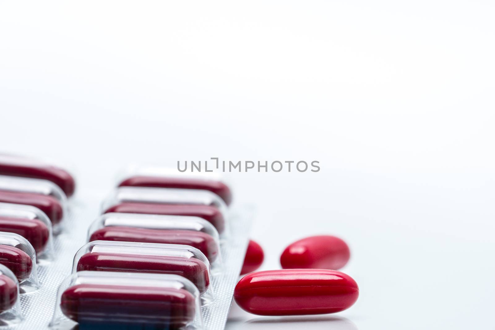 Red capsule pills and blister pack isolated on white background with copy space. Vitamin and supplement for pregnancy and elderly people. Pharmaceutical industry. Pharmacy background. Global healthcare concept.