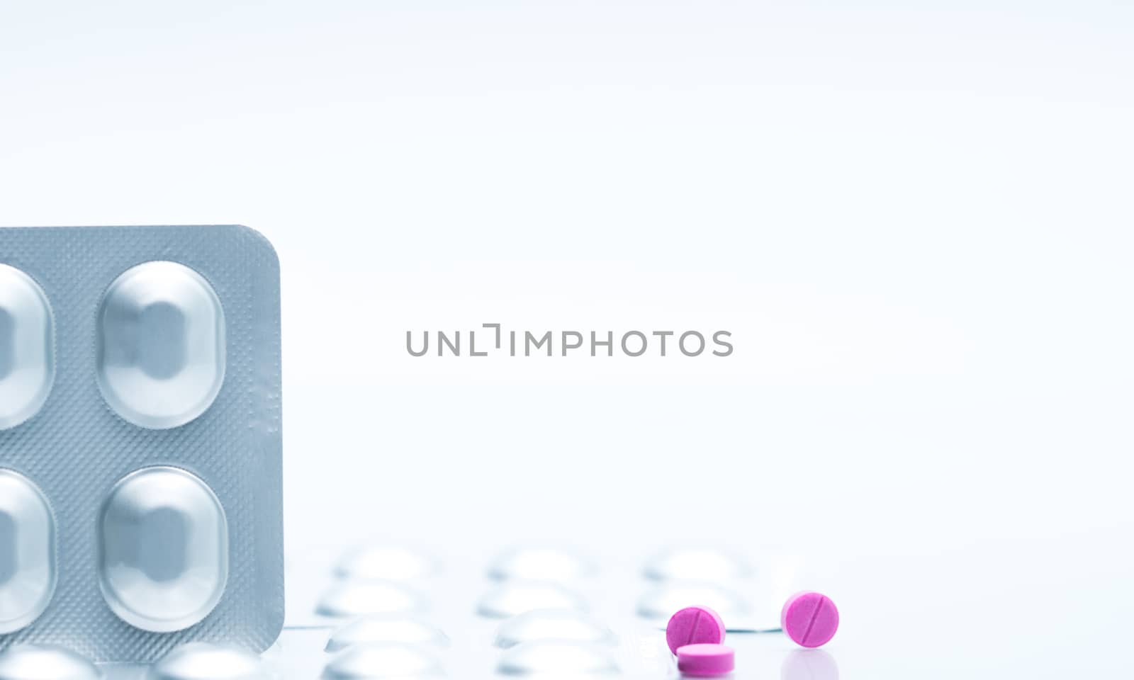 Macro shot of small pink tablets pills and silver aluminium foil blister pack of antihistamine pills on white background and copy space for text. Medicine for asthma treatment concept. Pharmaceutical industry. Pharmacy background. Global healthcare concept. by Fahroni