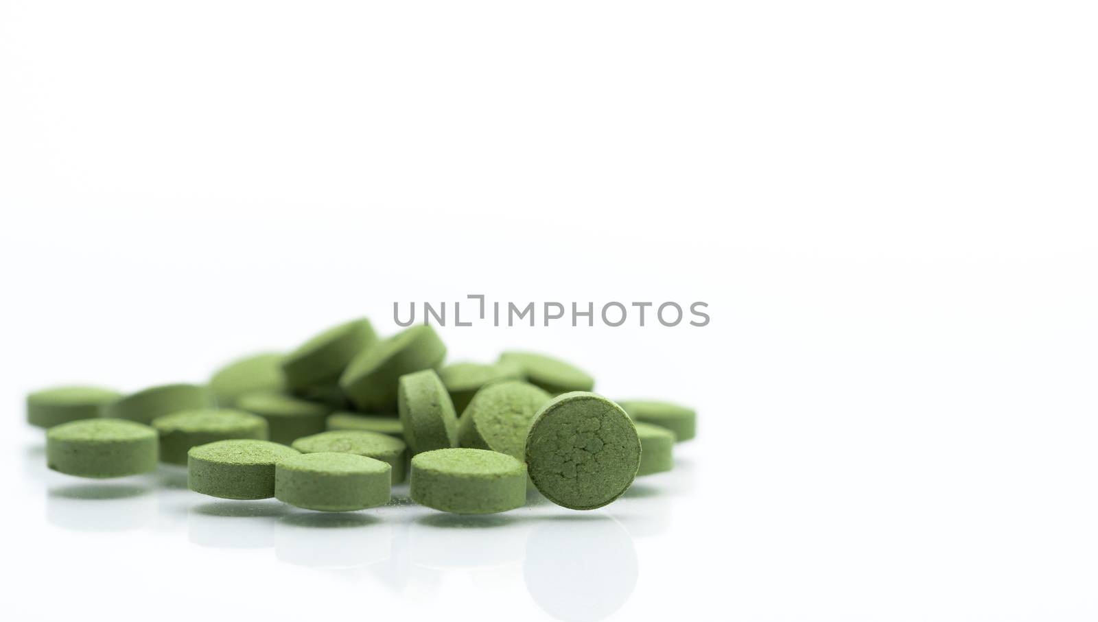 Close up Andrographis paniculata herbal medicine tablets pills. Antipyretic, relieve sore throat green alternative herbal medicine tablets on blur tablet background. Pharmaceutical industry. Pharmacy background. Global healthcare.