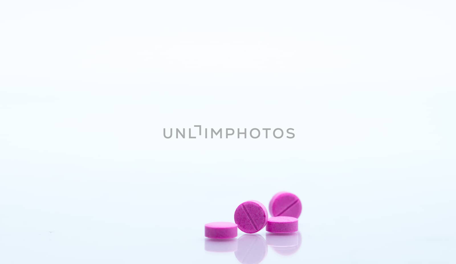 Macro shot of four small pink tablets pills isolated on white background with copy space for text. Medicine for asthma treatment concept. Pharmaceutical industry. Pharmacy background. Global healthcare concept. Health budgets and policy.