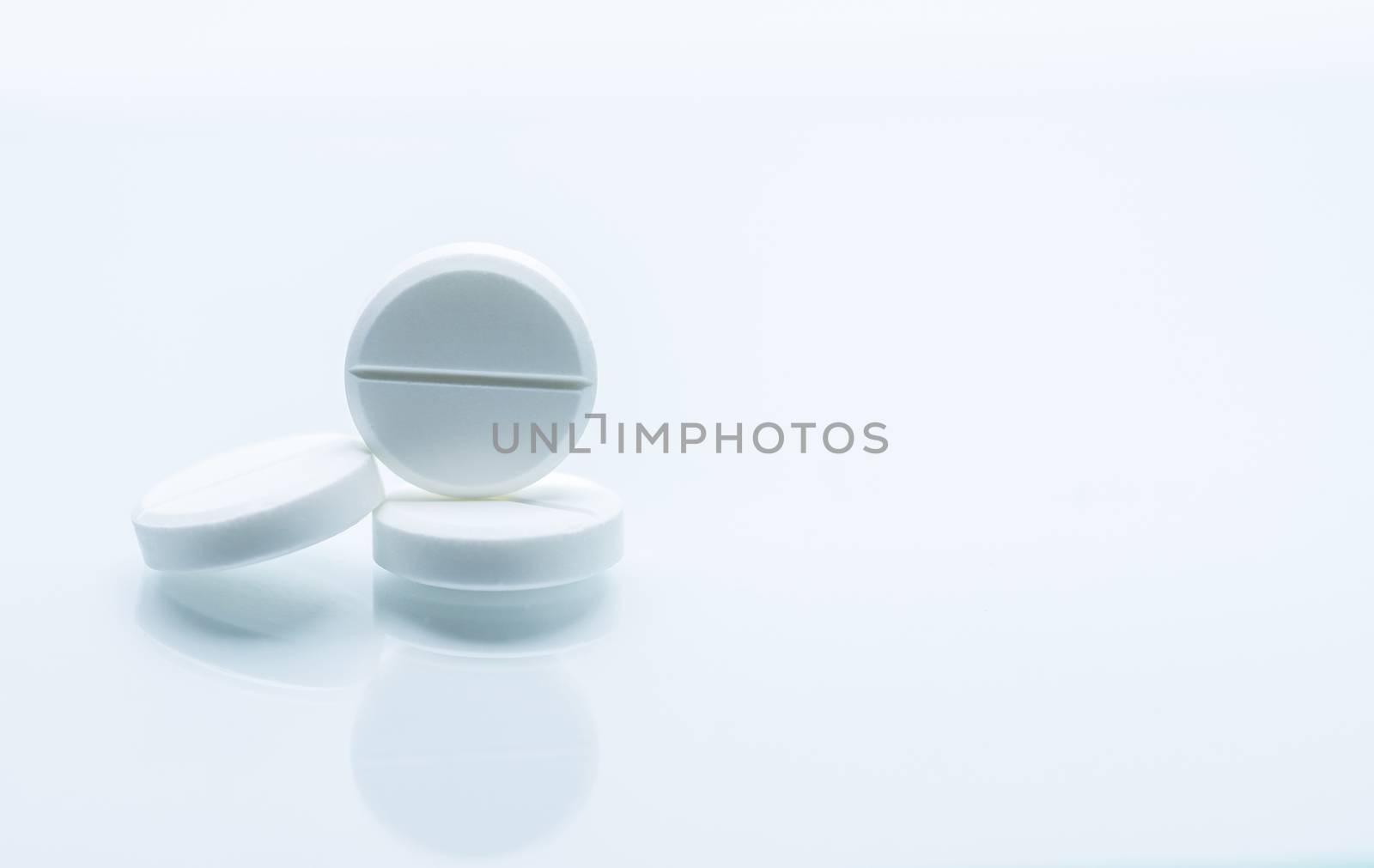 Macro shot of three white chewable tablets on white background with shadows. Antacids pills for relief stomachache from excess gastric acid in stomach. Stress induce gastric ulcer treatment concept. Pharmaceutical industry. Pharmacy background. Global healthcare concept. Health budgets and policy.