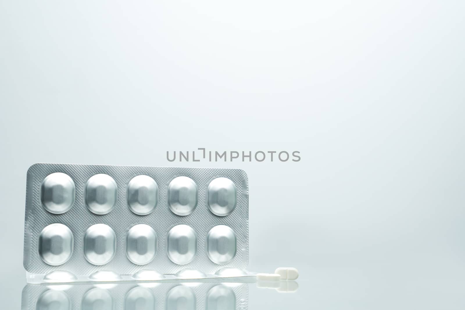 Silver aluminium foil blister pack of pills with on white background with shadows and copy space for text. Pharmaceutical packaging and medicine storage concept. Pharmaceutical industry. Pharmacy background. by Fahroni