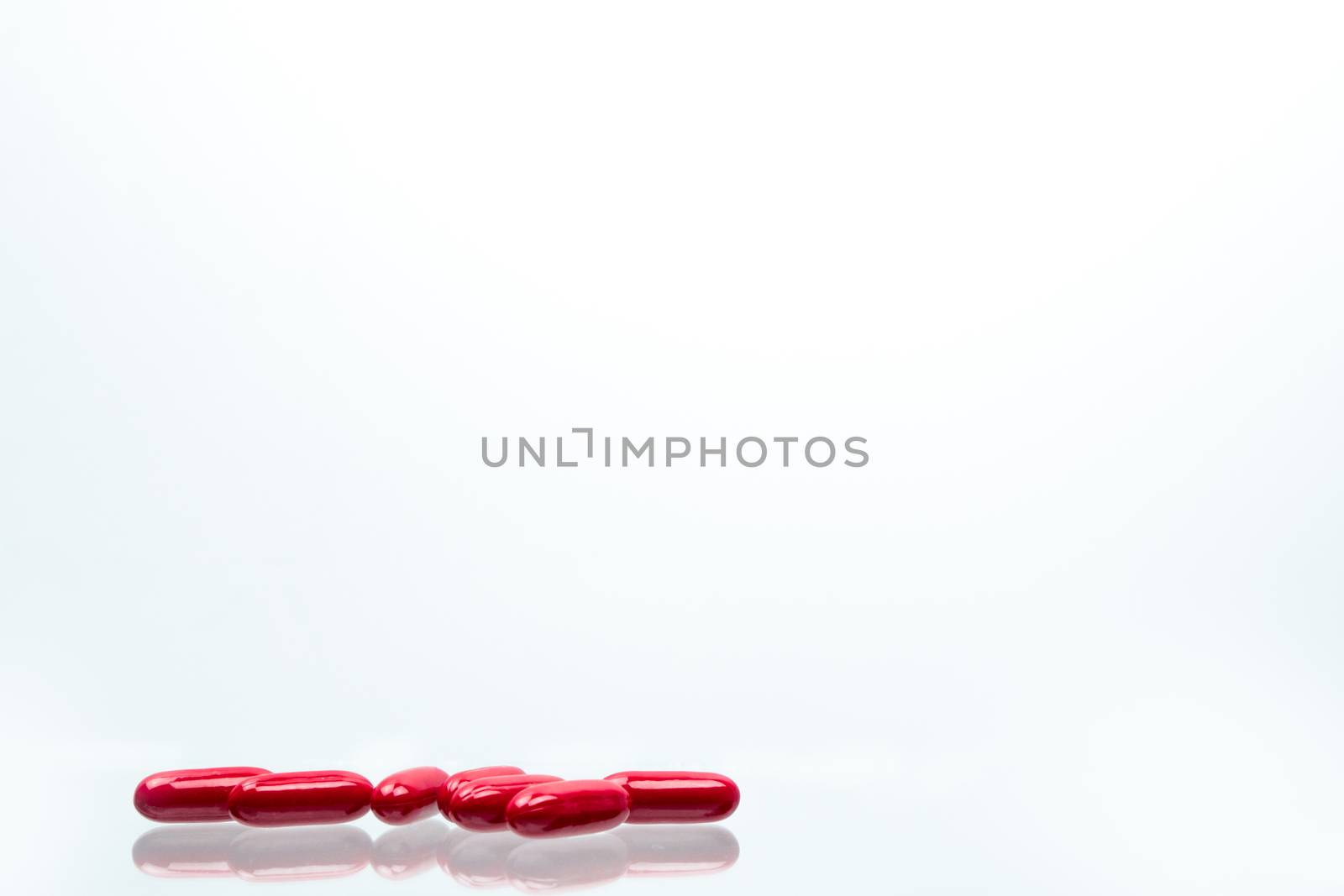 Red capsule pills isolated on white background with shadows and copy space for text. Vitamin and supplement for pregnancy and elderly people. Pharmaceutical industry. Pharmacy background. Global healthcare concept.