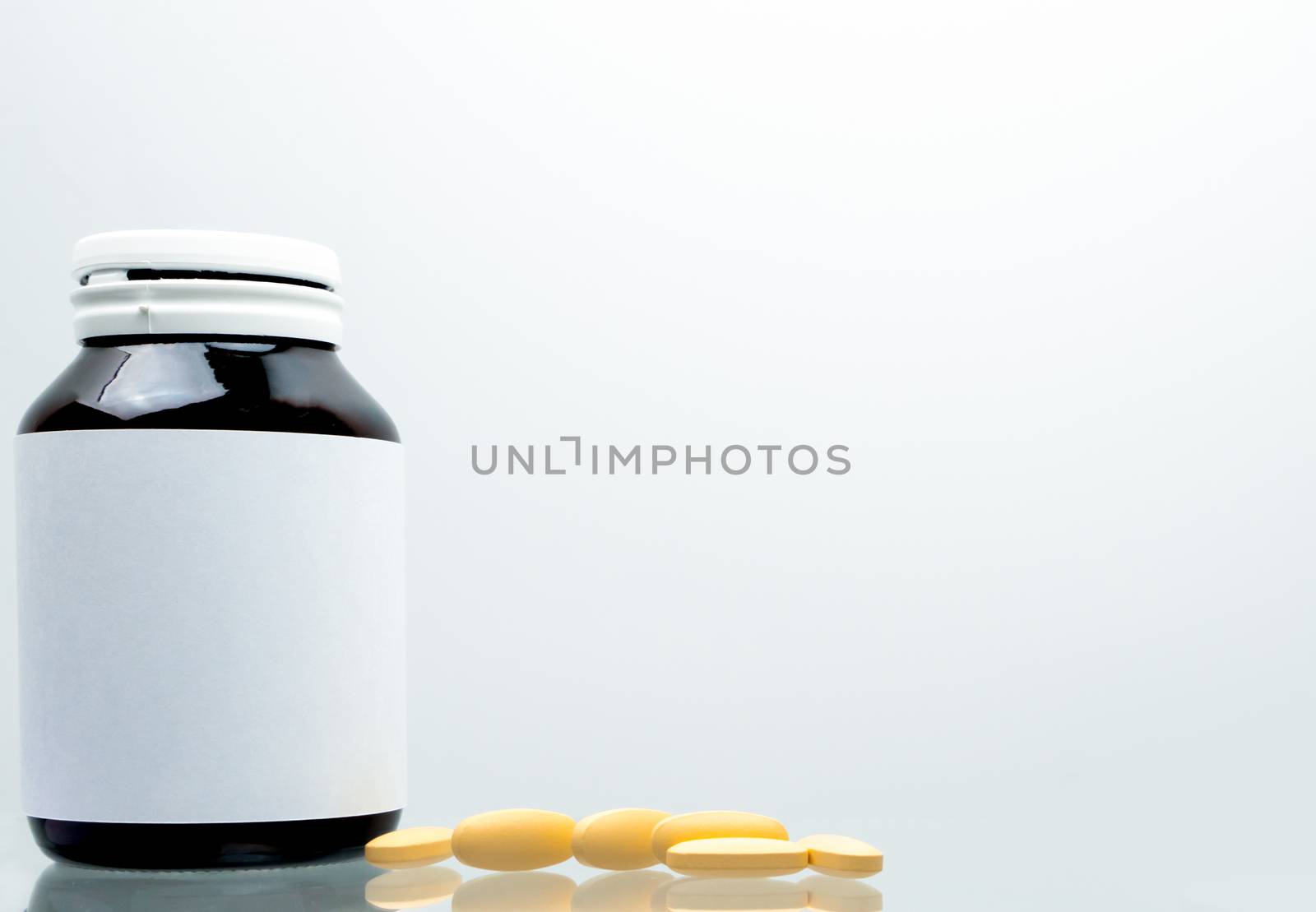 Tablets pills of vitamin C 1,000 mg on white background and amber bottle with blank label and copy space for text. Vitamin and supplement concept. Antioxidant. Pharmaceutical industry. Pharmacy background. Global healthcare.