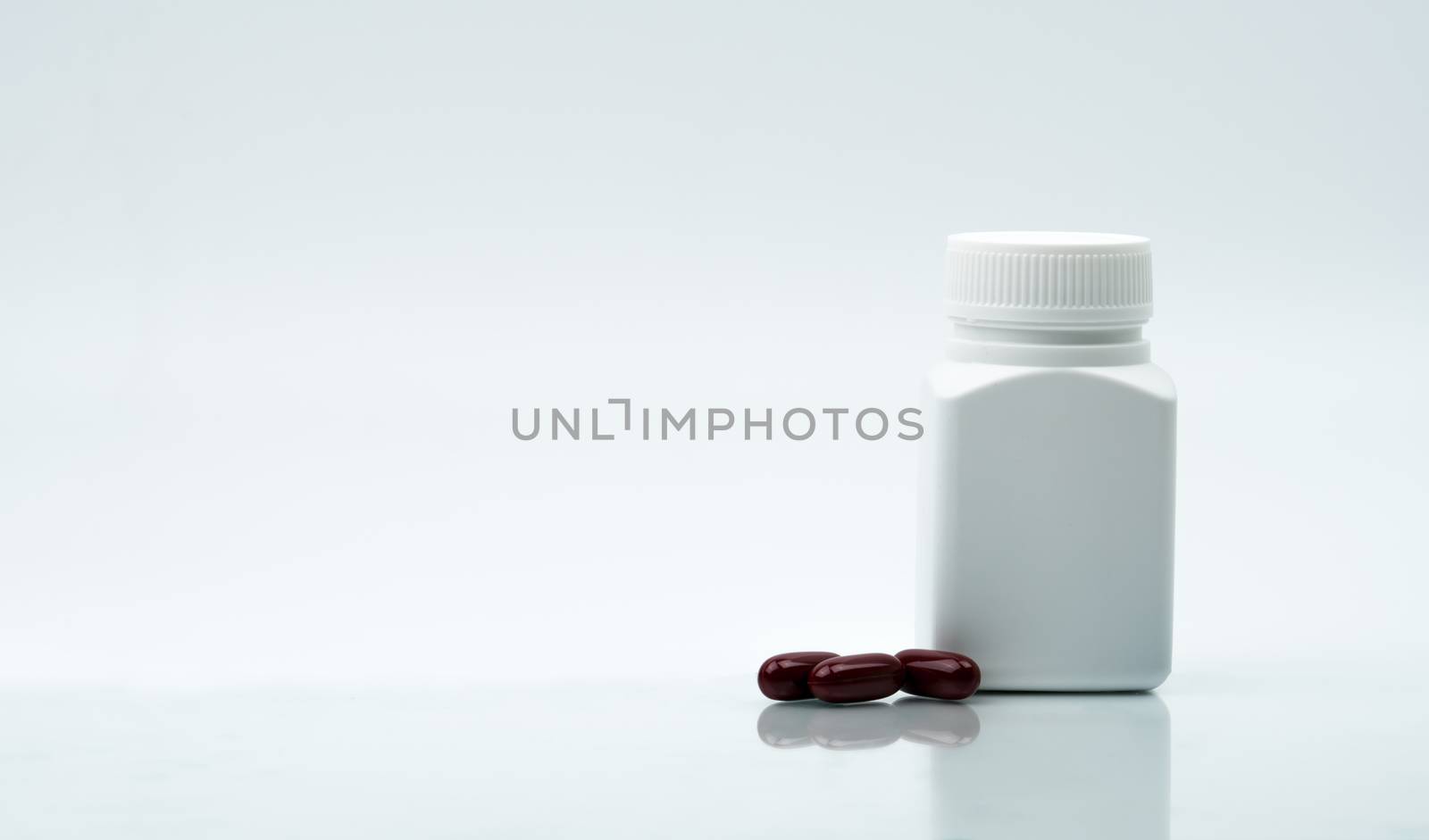 Macro shot of multivitamins capsule pills and closed plastic bottle with blank label and copy space on white background. Vitamins and supplements for hard working guy. Global healthcare concept