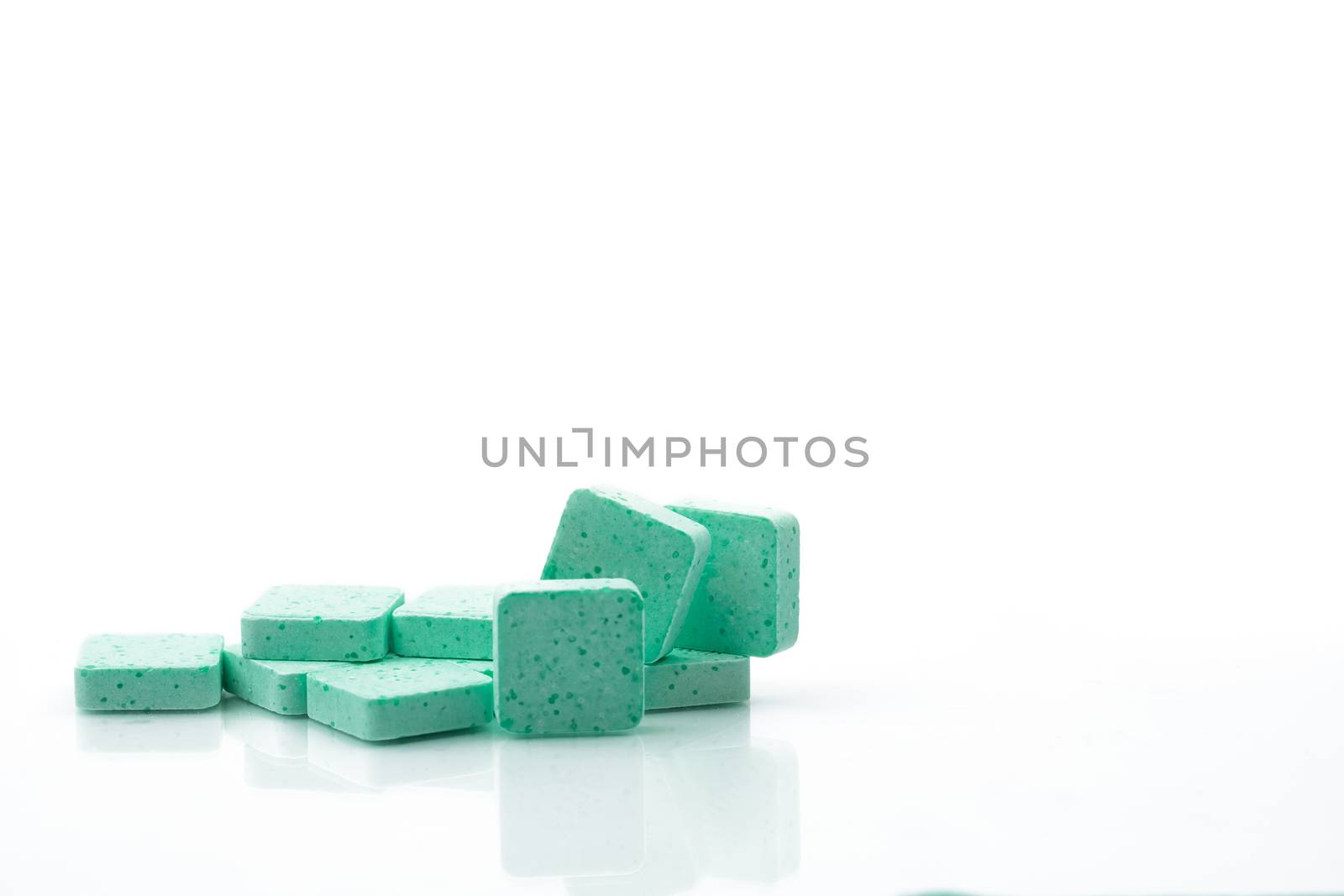 Macro shot to show detail of green medical lozenges for relief cough, sore throat and throat irritation on white background with copy space. Apple flavored. Pharmaceutical industry. Pharmacy background. by Fahroni