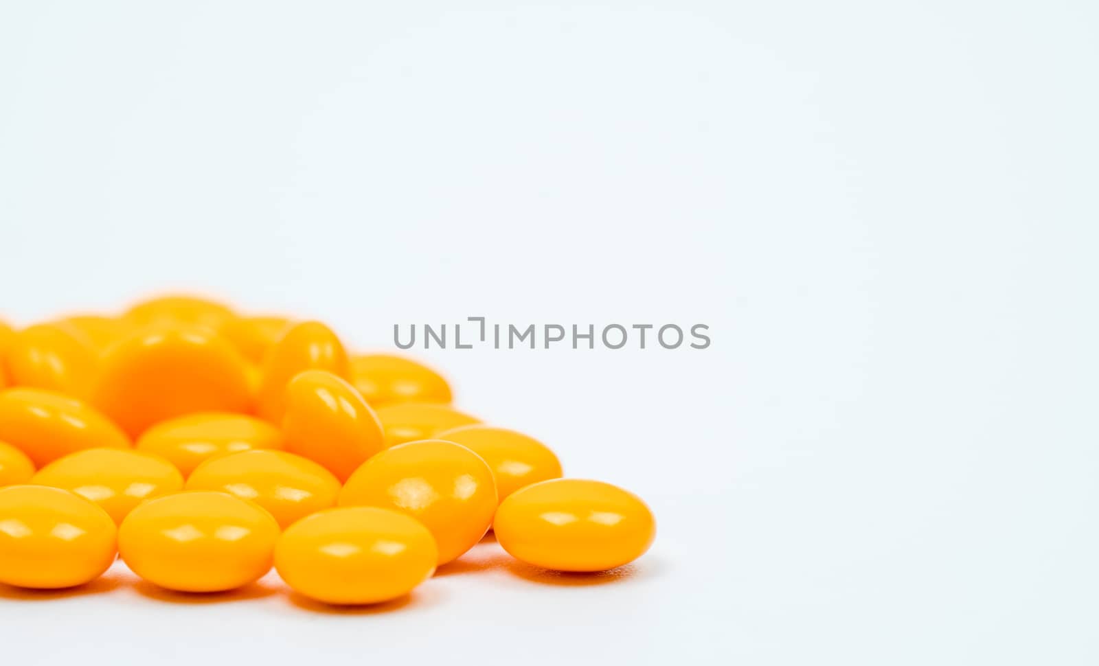 Yellow sugar coated tablets pills on white background with copy space. Medicine for treatment constipation. Pharmaceutical industry. Pharmacy background. Global healthcare concept. Health budgets and policy.