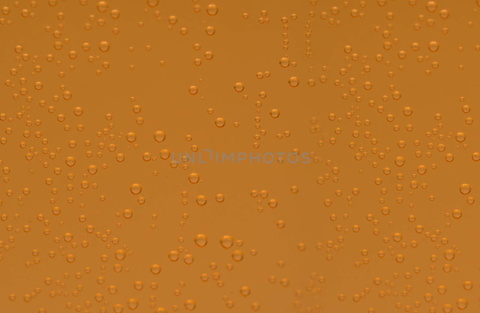Macro shot of orange effervescent bubbles of calcium and vitamin C effervescent tablets in transparent glass. Orange color texture background.
