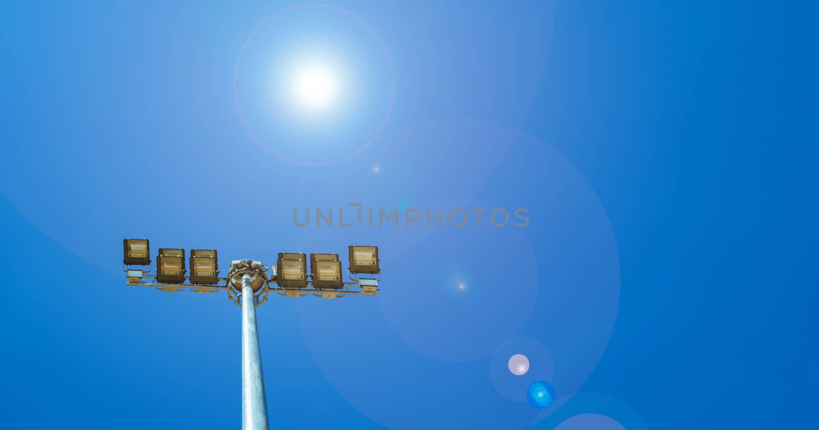 Sport lights of the stadium on beautiful blue sky with flare light. Copy space by Fahroni