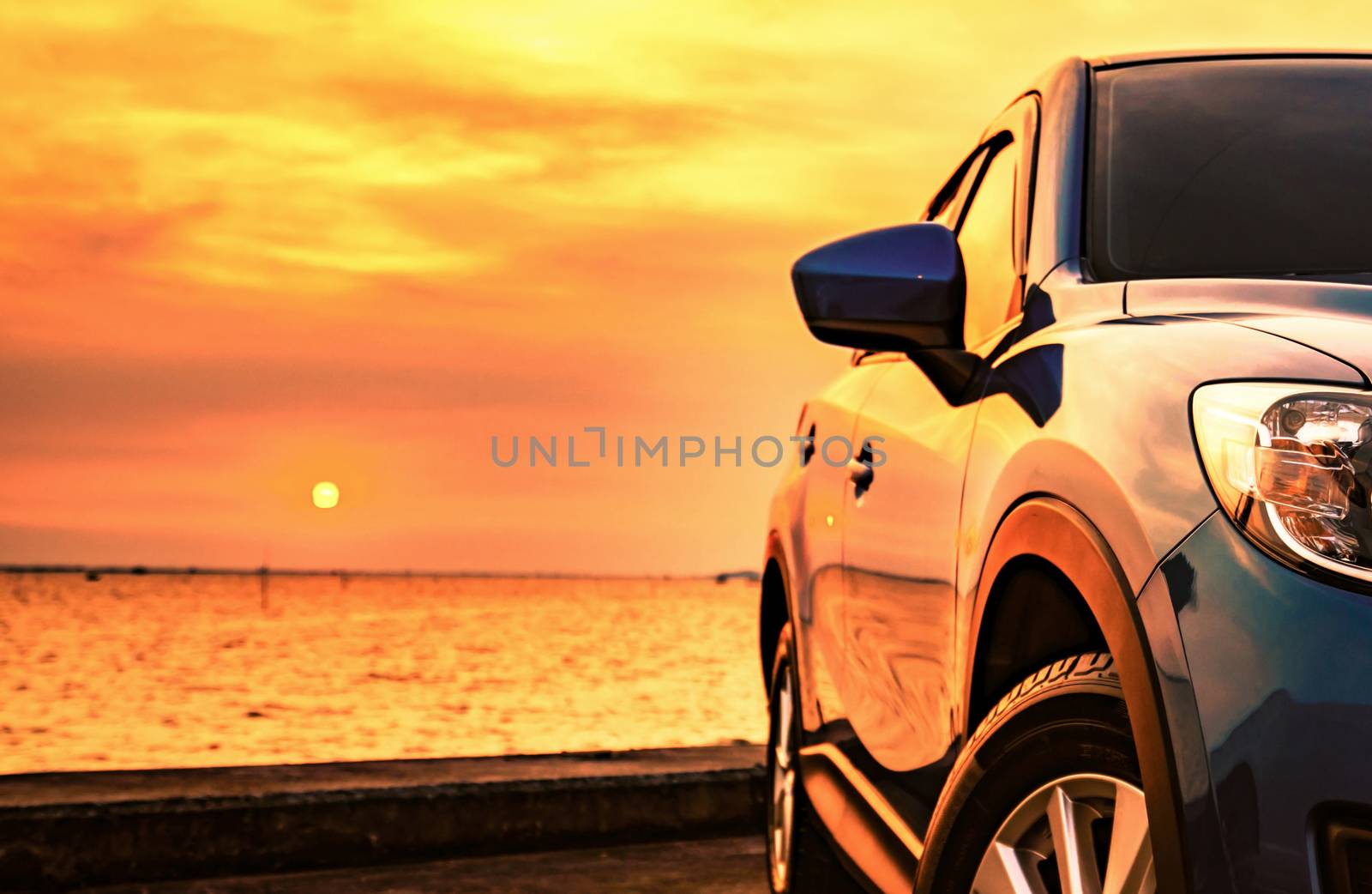 Blue compact SUV car with sport and modern design parked on concrete road by the sea at sunset. Environmentally friendly technology. Business success concept. Automotive industry. Hybrid car and road trip concept. by Fahroni