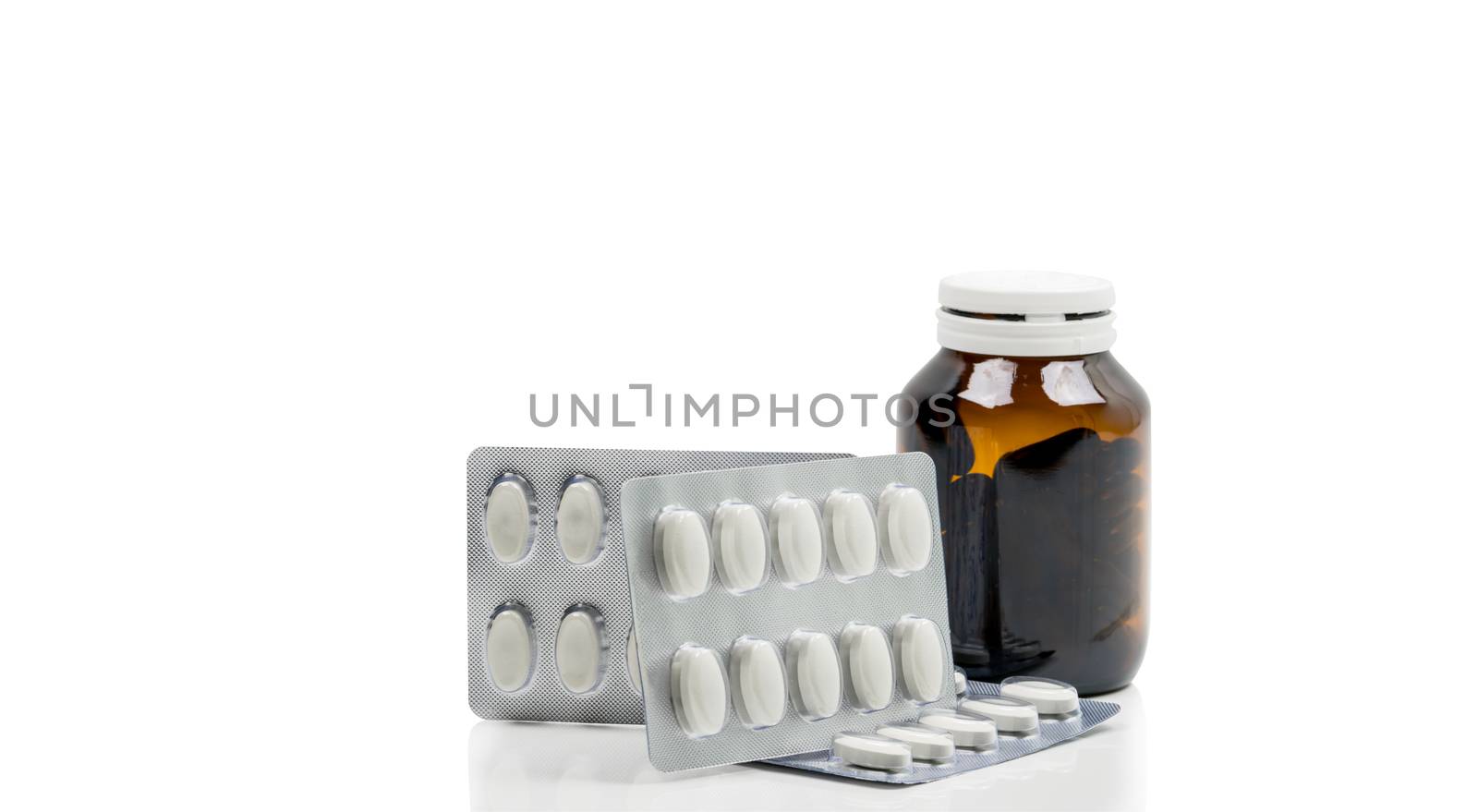 Vitamins capsule in amber glass bottle with blank label and supplements tablets in blister pack on white background. Antioxidants for healthy skin. Good supplement pills for woman bone.