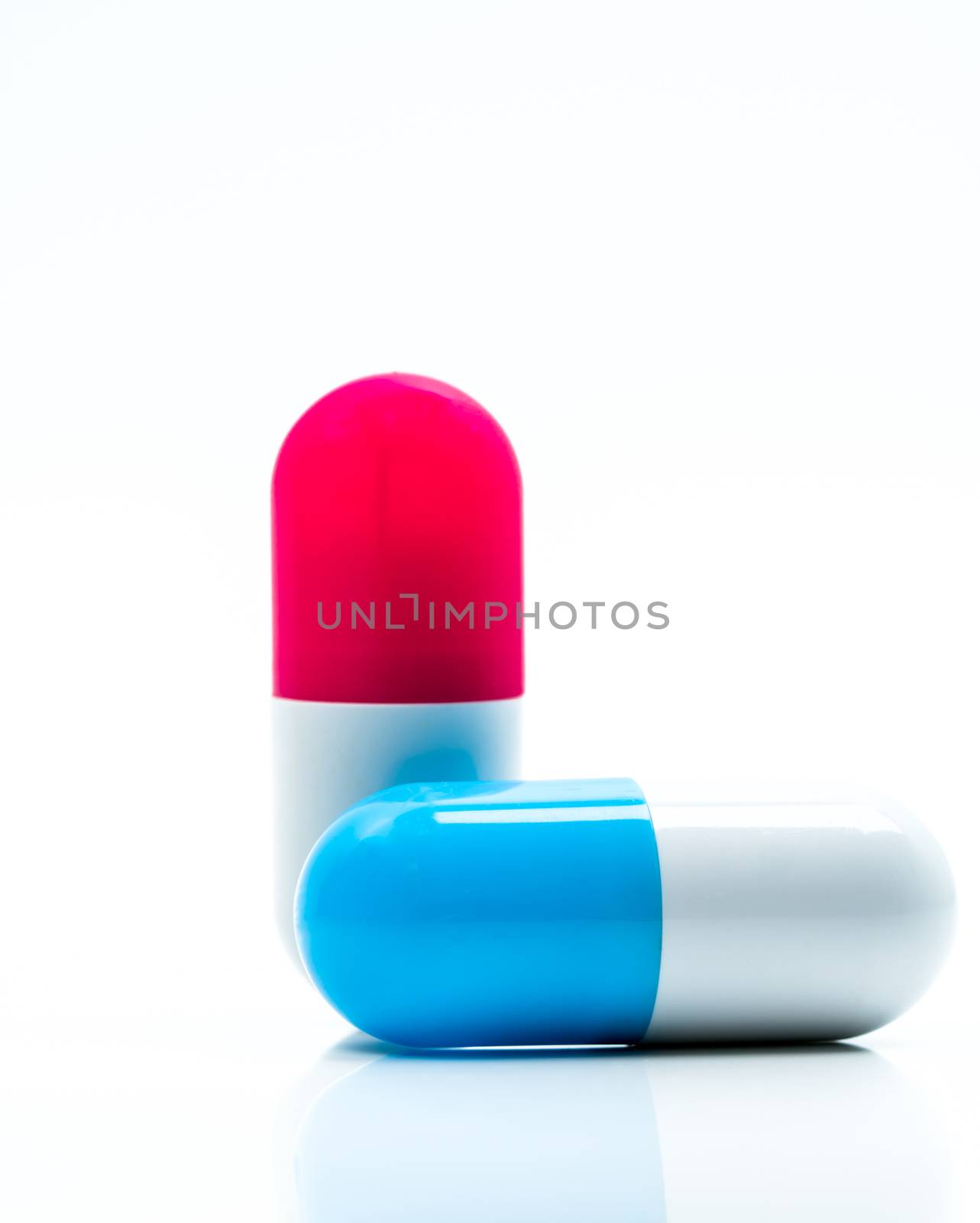 Two capsule pills isolated on white background. Global healthcare concept. Pharmacy sign and symbol. Pharmaceutical industry. Pharmacy background. Global healthcare concept. Antibiotic or antimicrobial drug resistance. Health budgets and policy. Blue-white and red-white antibiotic capsule.
