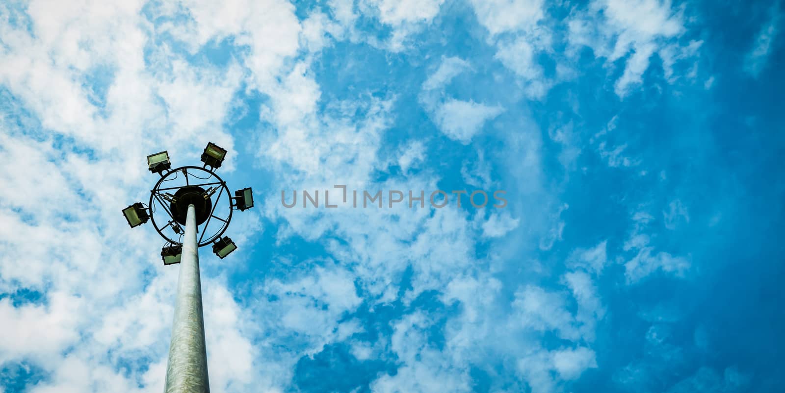Sport lights of the stadium with pole on beautiful blue sky and white cumulus clouds with copy space for text. by Fahroni