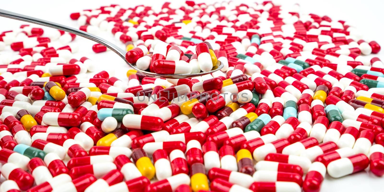 Antibiotic capsules pills in stainless steel spoon on white background with copy space. Drug resistance concept. Antibiotics drug use with reasonable and global healthcare concept. Pharmaceutical industry. Pharmacy background.