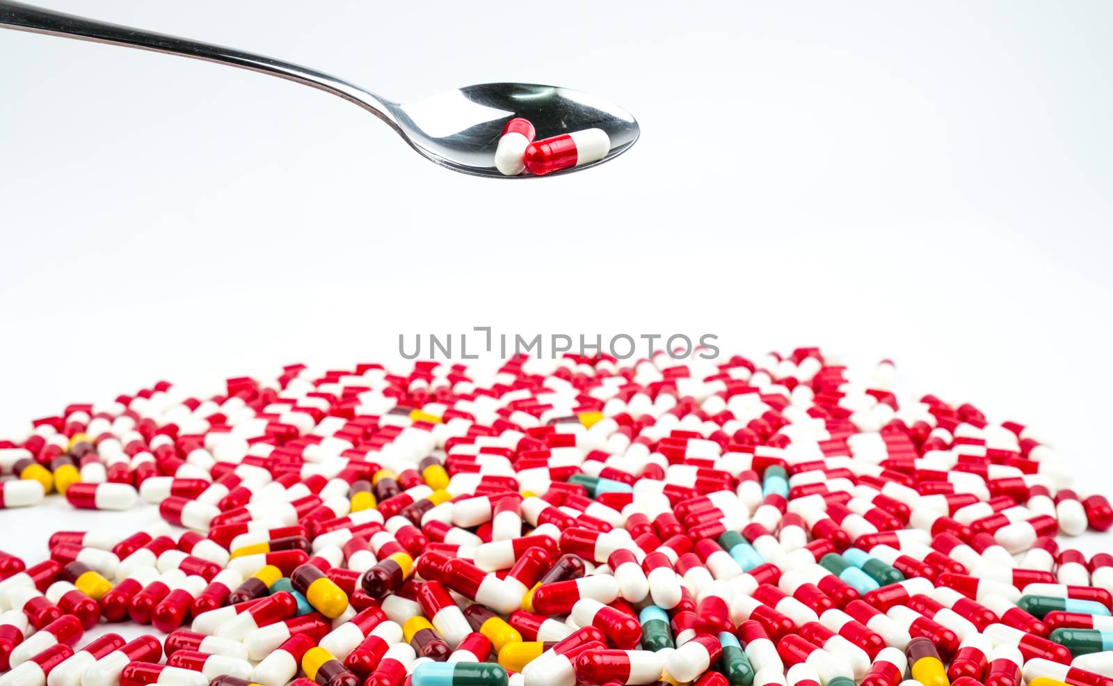 Antibiotic capsules pills in stainless steel spoon on white background with copy space. Drug resistance concept. Antibiotics drug use with reasonable and global healthcare concept. Pharmacy background.