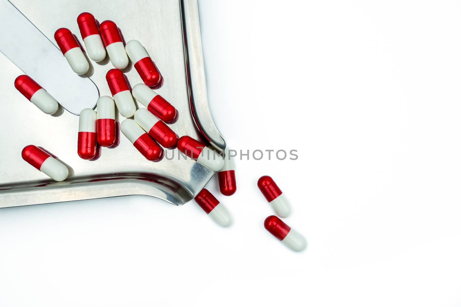 Top view of red, white antibiotic capsules pills on stainless steel drug tray. Drug resistance, antibiotic drug use with reasonable, health policy and health insurance concept. Pharmaceutical industry. Pharmacy background.