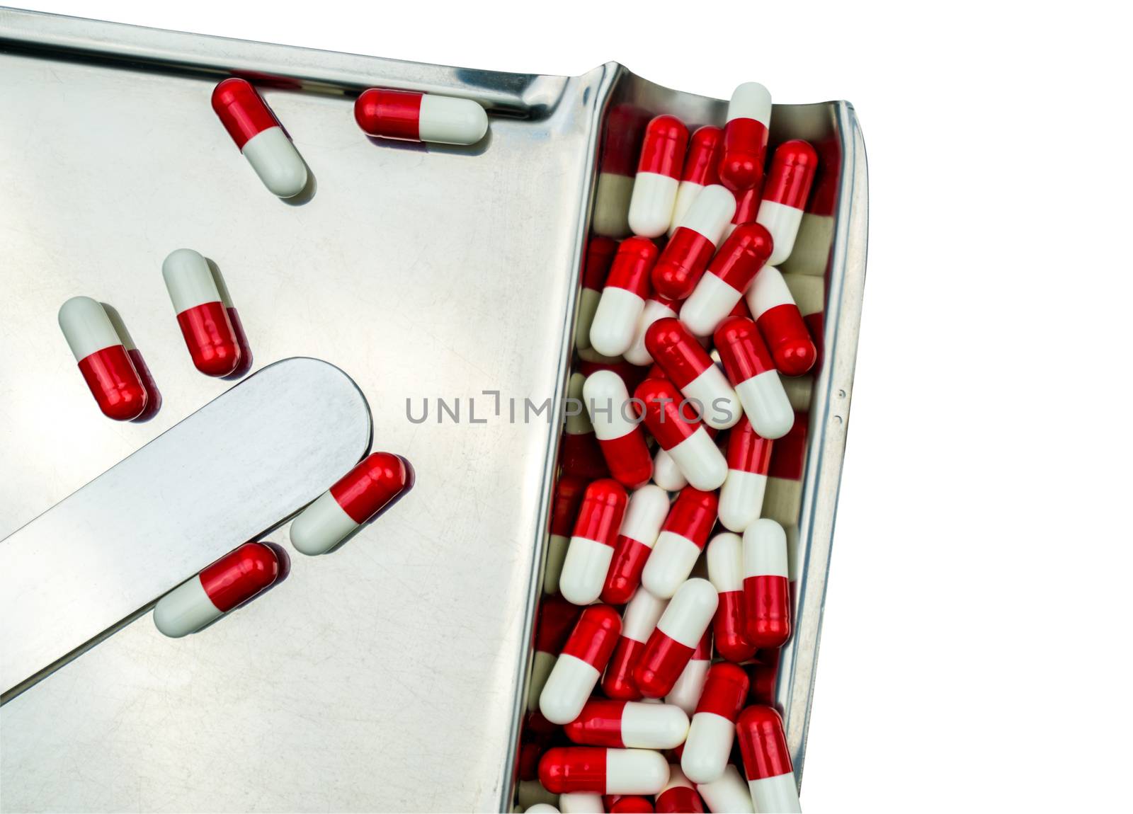 Top view of red, white antibiotic capsules pills isolated on stainless steel drug tray with clipping path, drug resistance concept. Drug use with reasonable.