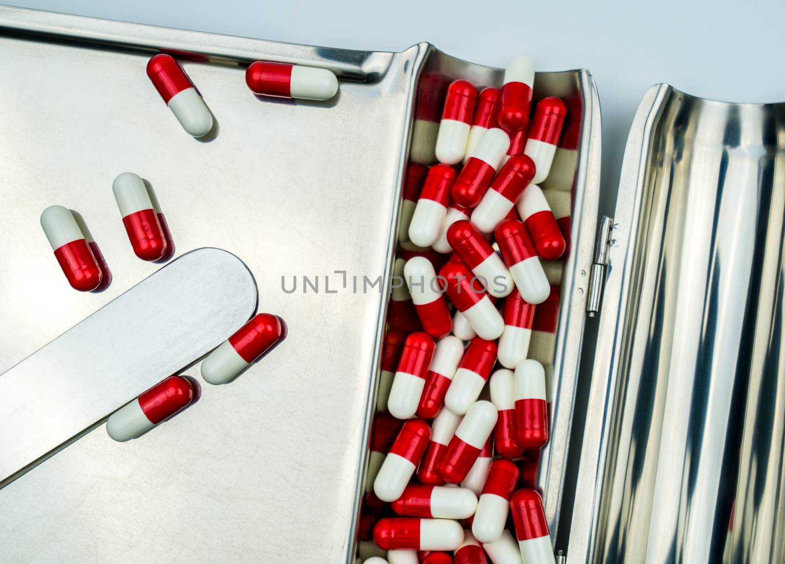 Top view of red, white antibiotic capsules pills on stainless steel drug tray. Drug resistance, antibiotic drug use with reasonable, health policy and health insurance concept. Pharmaceutical industry. Pharmacy background.