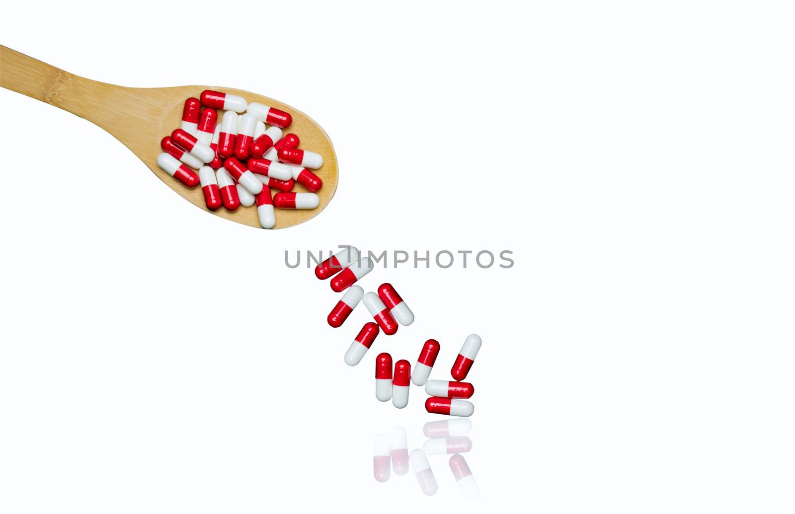 Colorful of antibiotics capsule pills in wooden spoon are spilling isolated on white background with copy space and clipping path. Antibiotic drug use with reasonable. Antibiotic overuse. Pharmaceutical industry. Pharmacy background. Health budgets and policy.