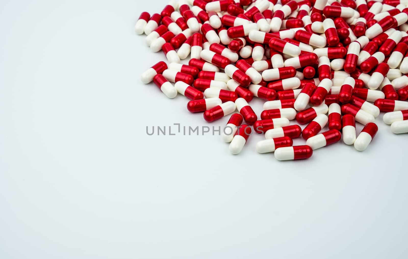 Red, white antibiotic capsules pills on white background with copy space. Drug resistance, antibiotic drug use with reasonable. Antibiotics drug overuse. Pharmaceutical industry. Pharmacy products.
