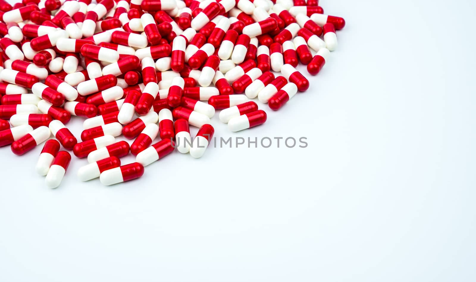 Red, white antibiotic capsules pills on white background with copy space. Drug resistance, antibiotic drug use with reasonable. Antibiotics drug overuse. Pharmaceutical industry. Pharmacy products.