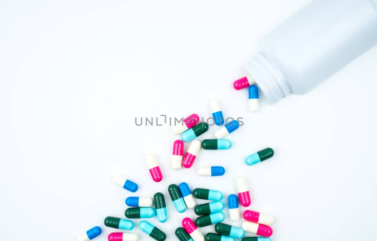 Antibiotic capsules spilling out of pill bottle on white background with copy space, just add your own text. Antibiotic drug use with reasonable concept. Antimicrobial drug overuse. Pharmaceutical industry. Pharmacy background. Global healthcare. Health budgets and policy concept.