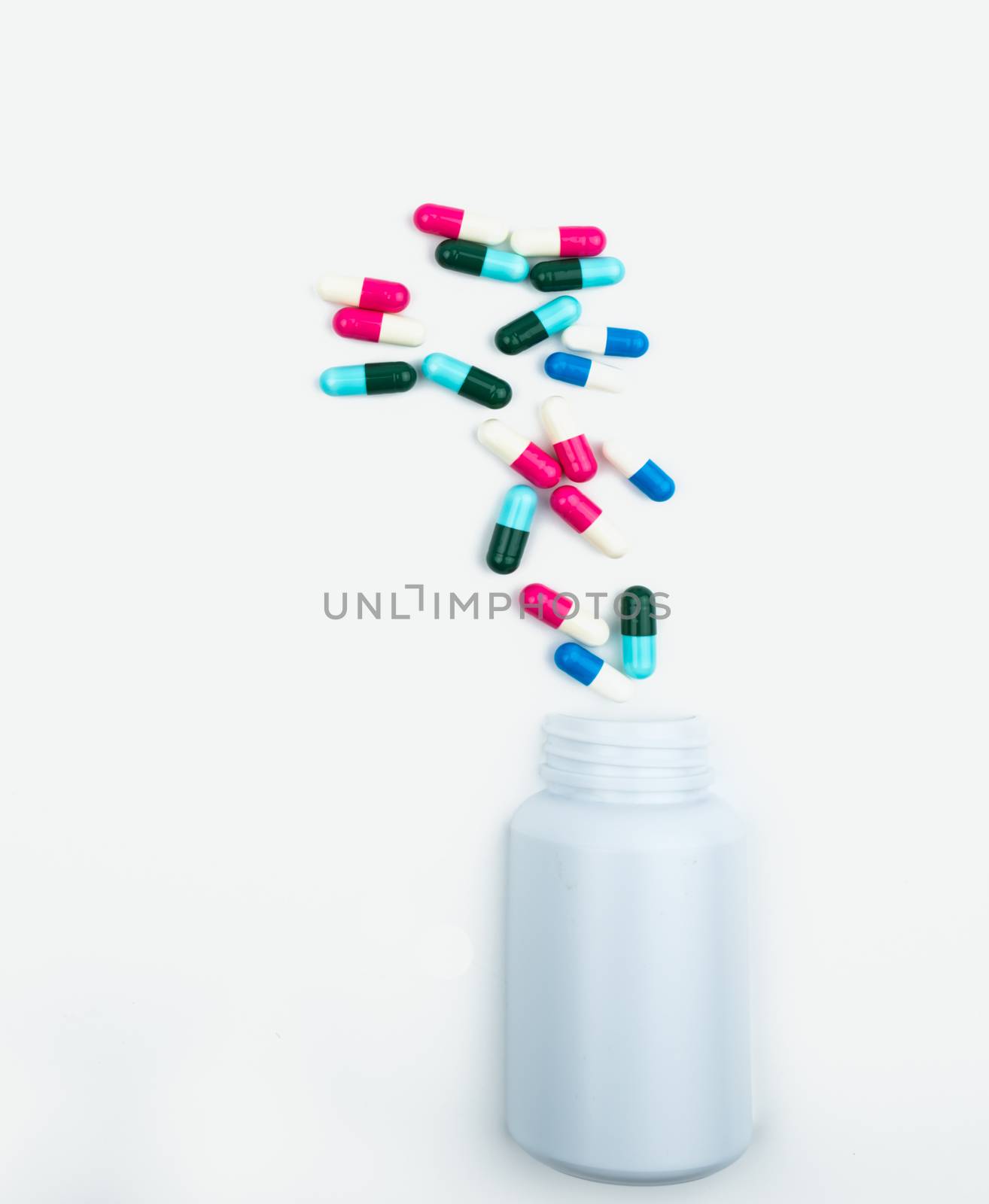 Pouring antibiotics capsule pills into plastic bottle isolated on white background with copy space. Drug storage, antibiotic drug use with reasonable, health policy and health insurance concept. Toxicology. Pharmaceutical industry. Pharmacy background.