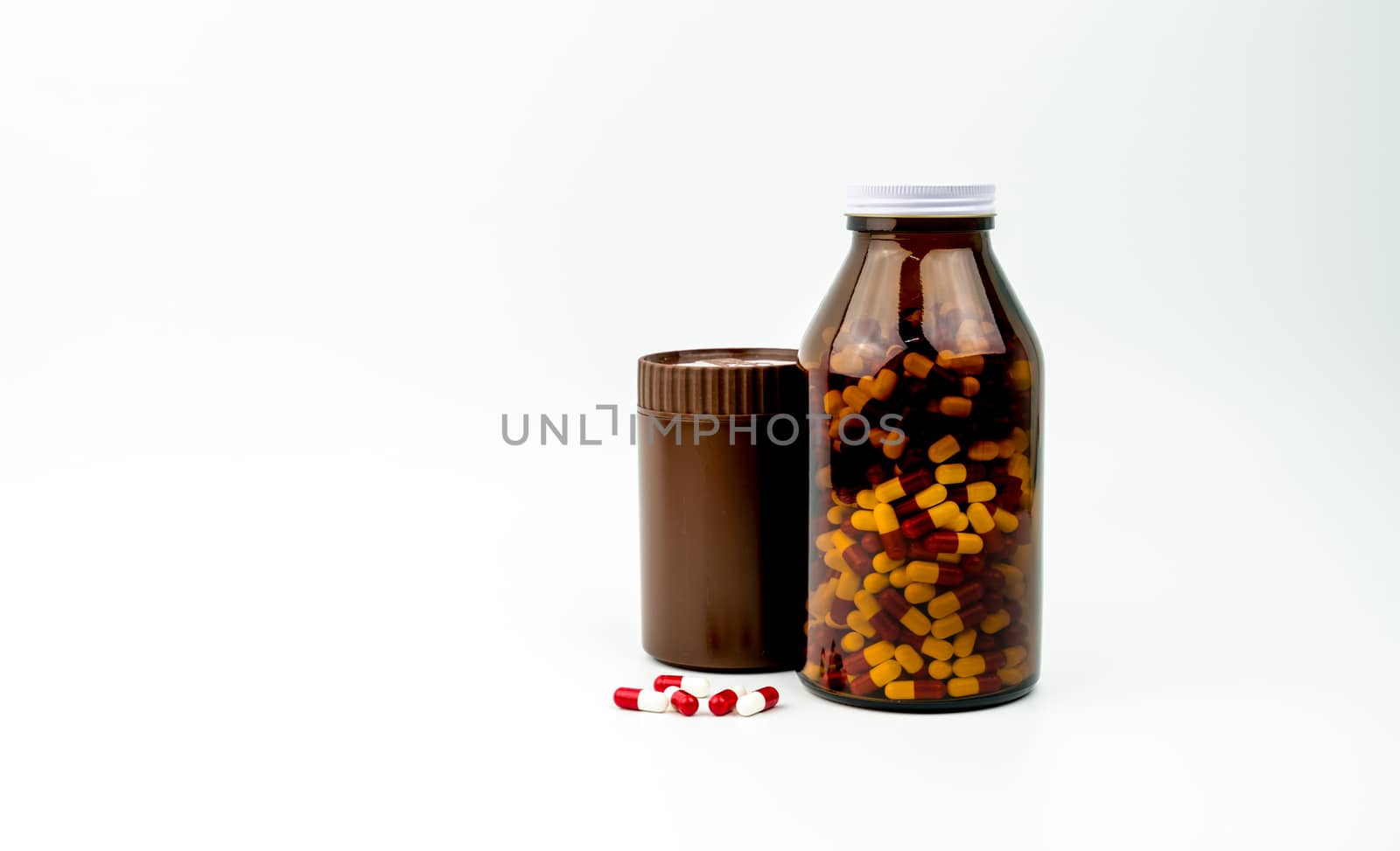 Red, white antibiotic capsules pills and two amber bottles isolated on white background with copy space and blank label. Drug resistance, antibiotic drug use with reasonable, health policy concept. Pharmaceutical industry. Pharmacy background.