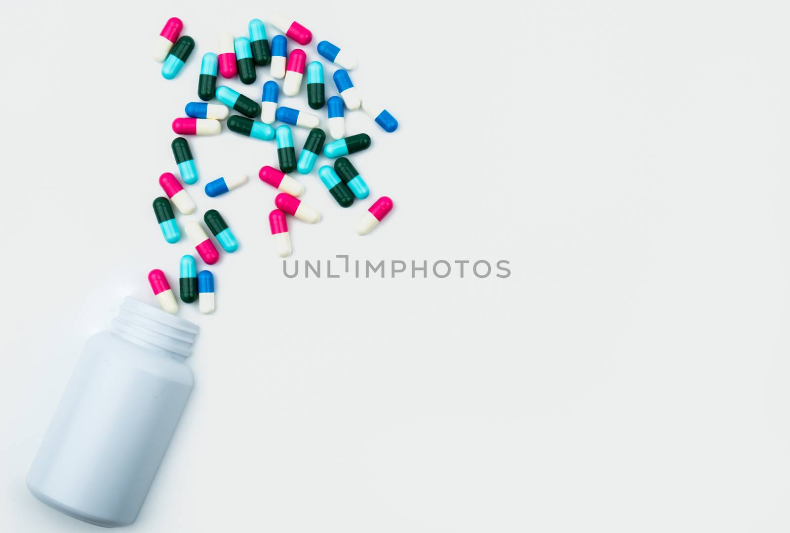 Pouring antibiotics capsule pills into plastic bottle isolated on white background with copy space. Drug storage, antibiotic drug use with reasonable, health policy and health insurance concept.