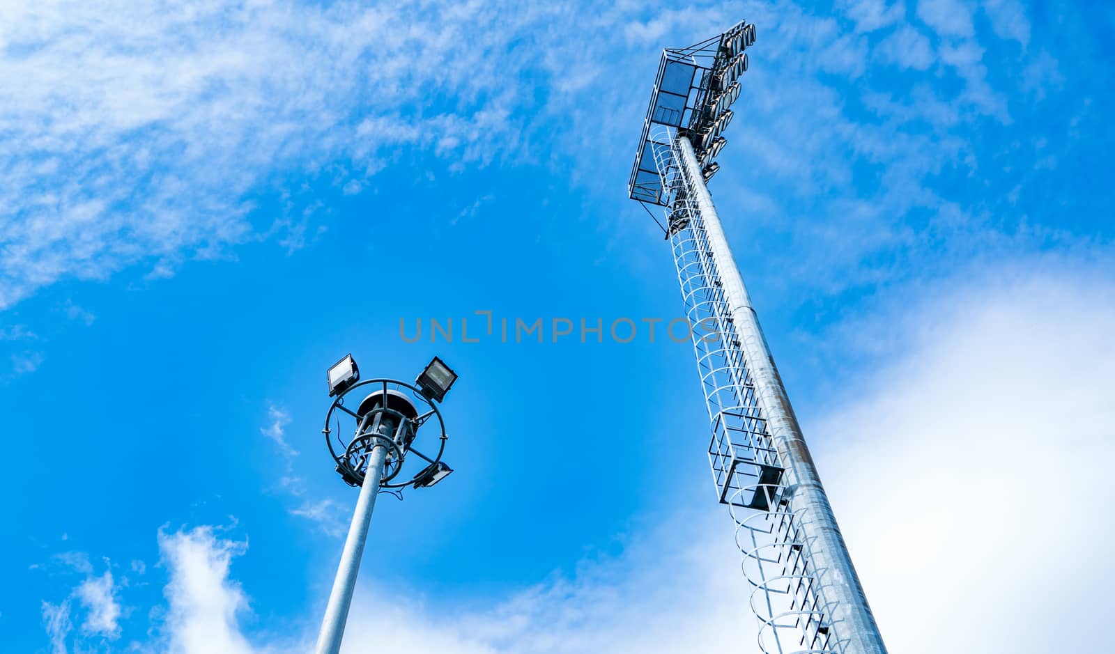 Sport lights of the stadium on beautiful blue sky and white clouds. Copy space