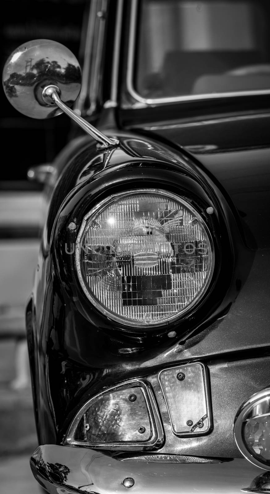 Black and white picture of front view of classic car with headlight