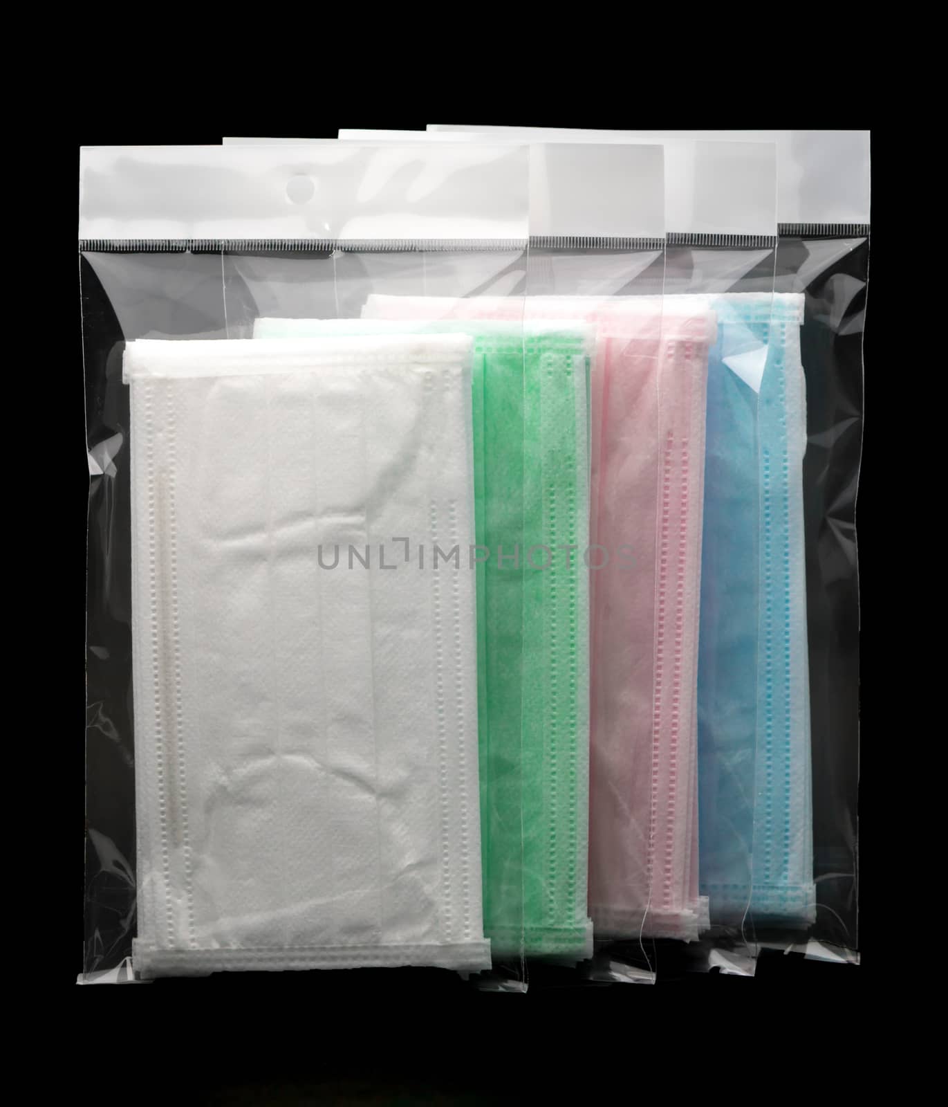 Green, pink, light blue and white ear loop disposable face mask in plastic bag overlapping, used for covering mouth and nose. It protects against body fluid and large particles in the air