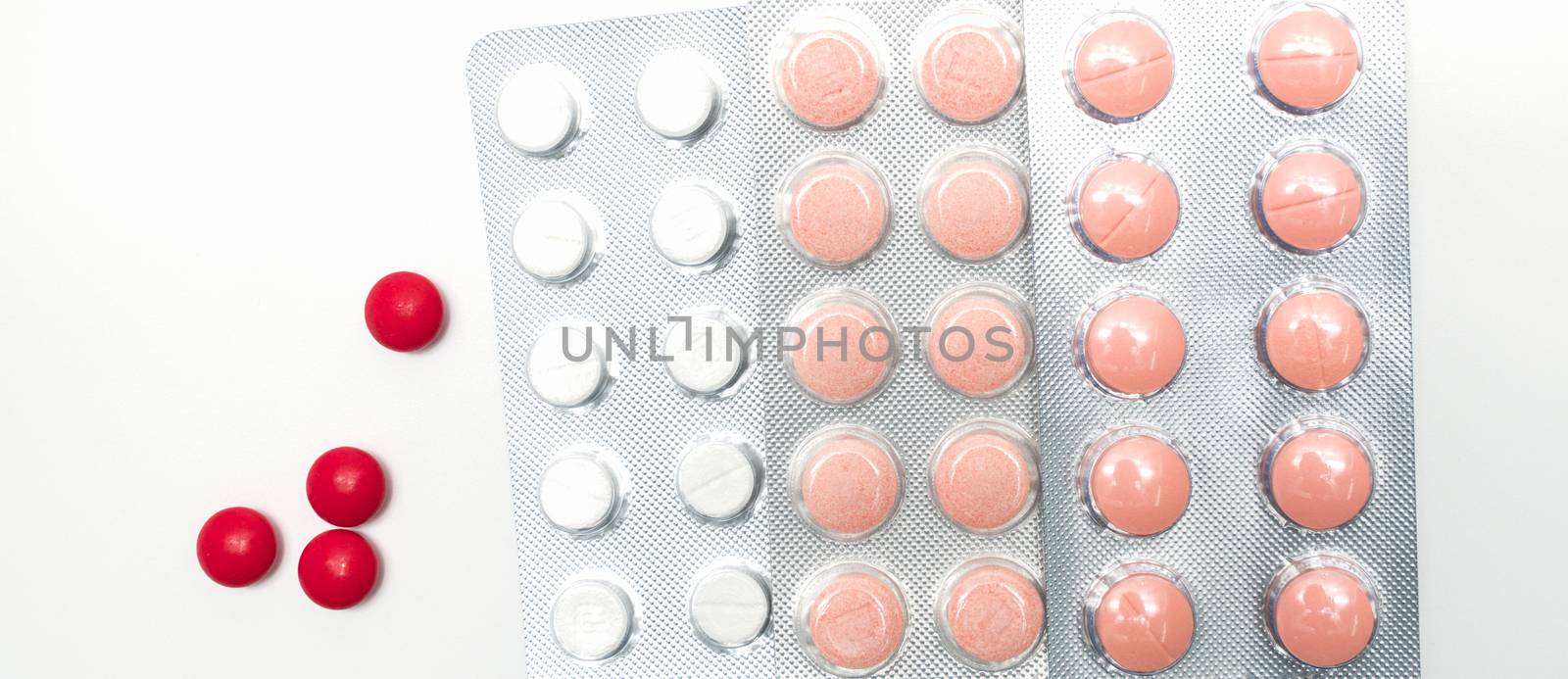 Red, orange and white tablet pills on white background