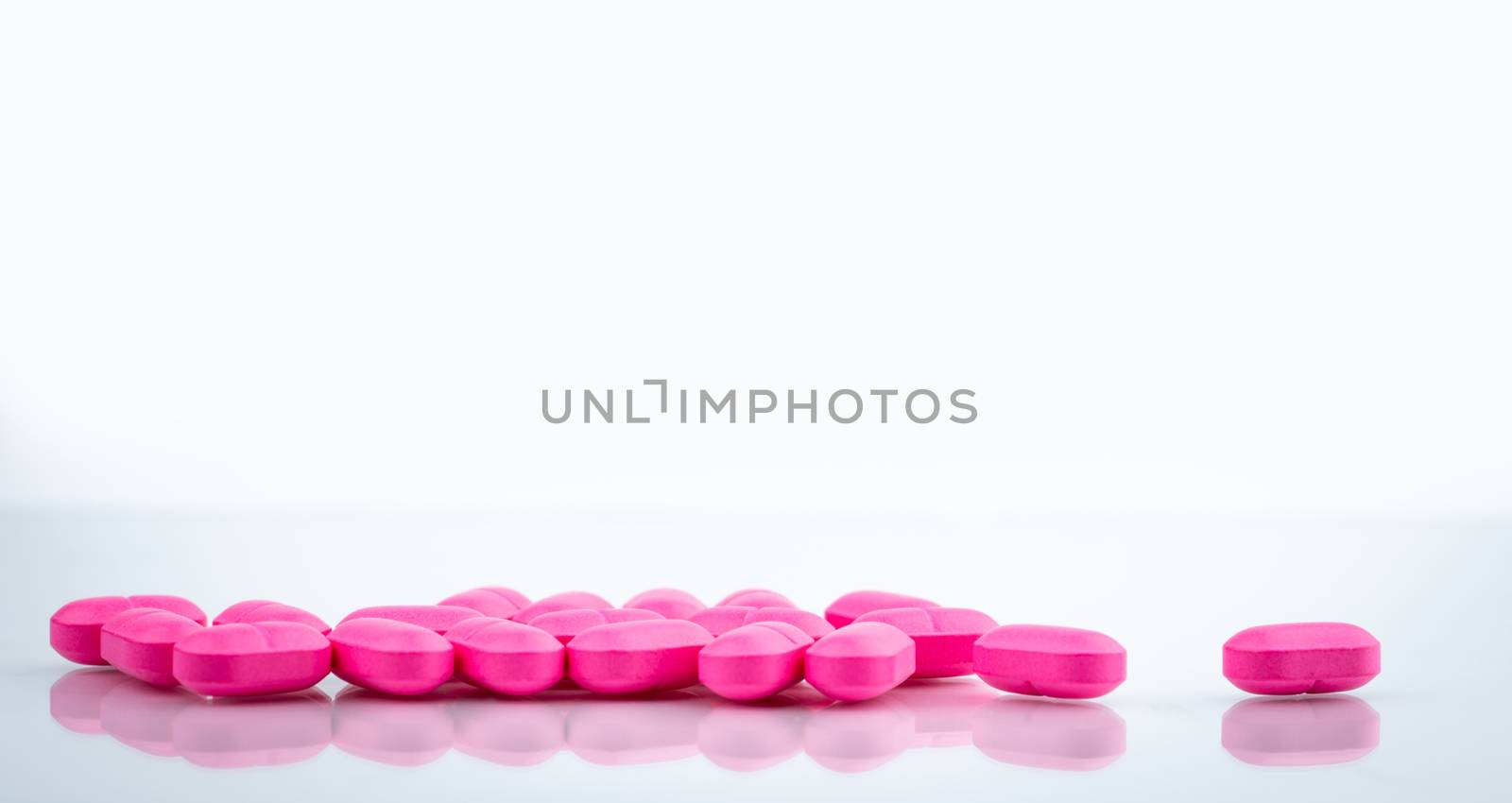 Pile of pink tablets pill isolated on white background. Norfloxacin 400 mg for treatment cystitis. Antibiotics drug resistance. Pink pills symbol of romantic love and healthcare for perfect couple.